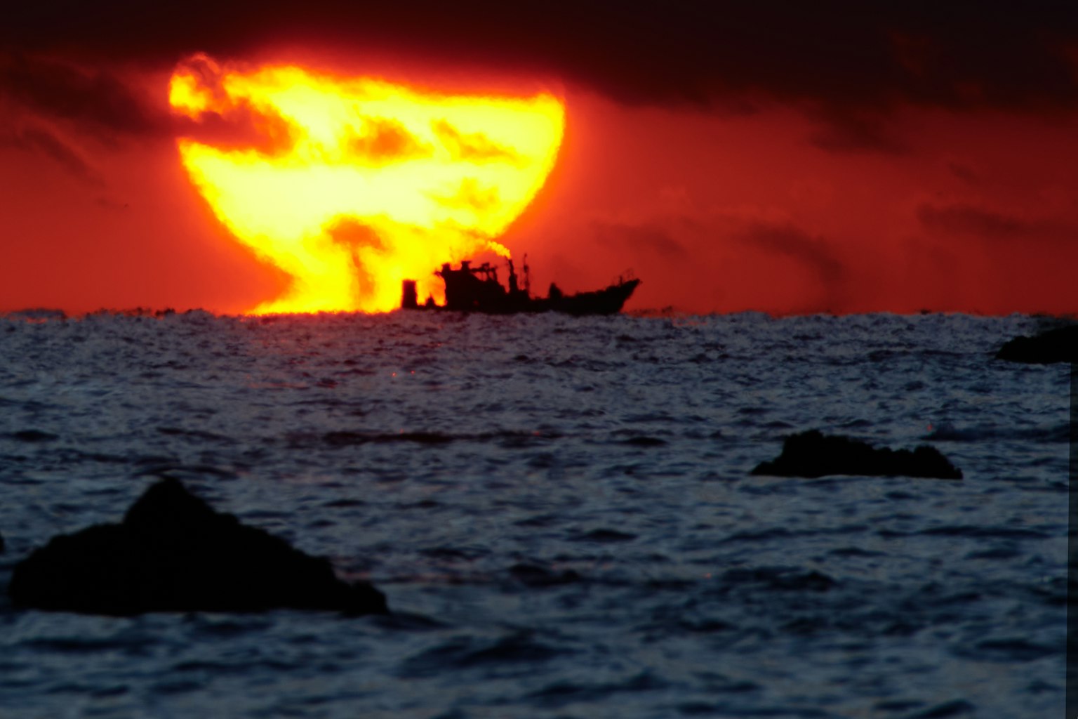 Silhouette di una barca contro un vivace tramonto sull'oceano