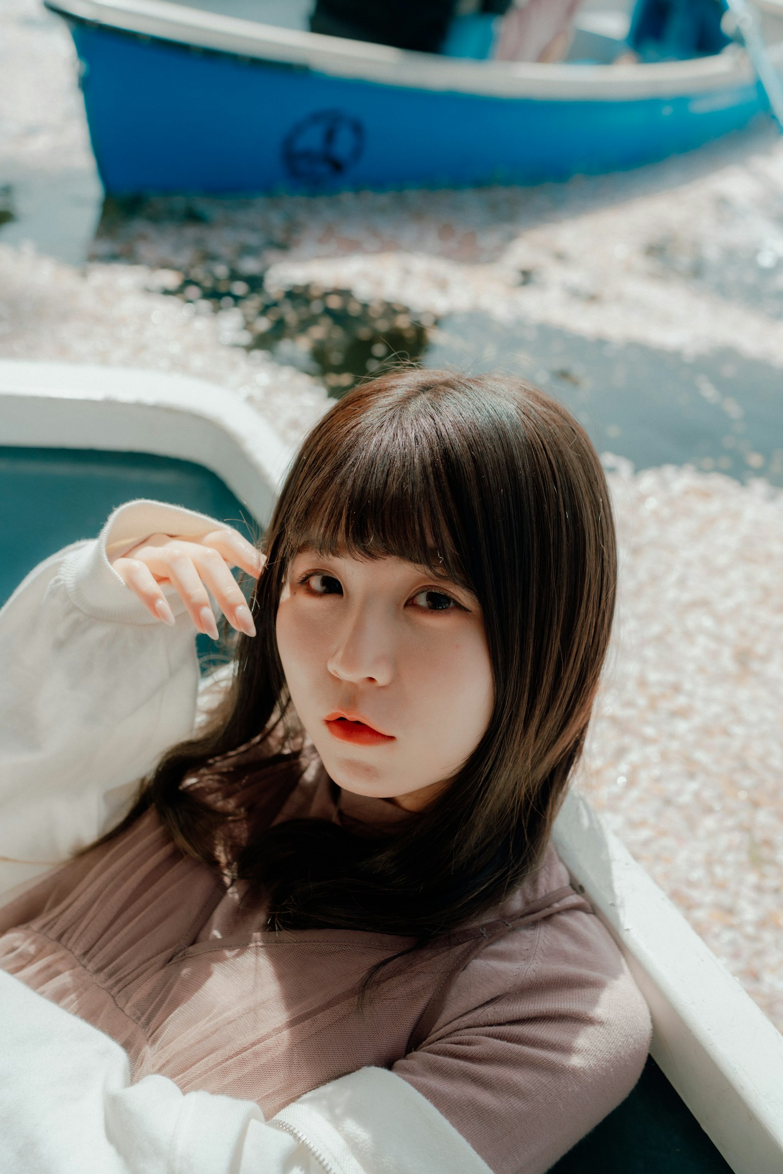 一位年轻女性坐在一只被樱花瓣包围的船上