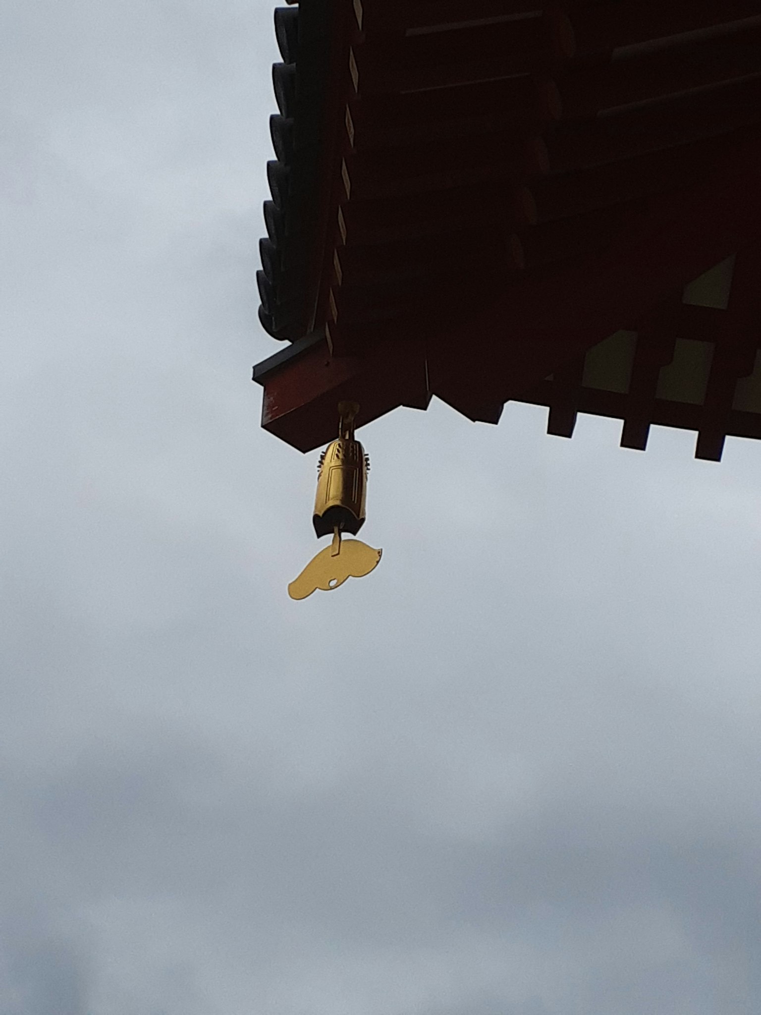 懸掛在華麗屋頂下的黃色燈籠與陰雲密布的天空