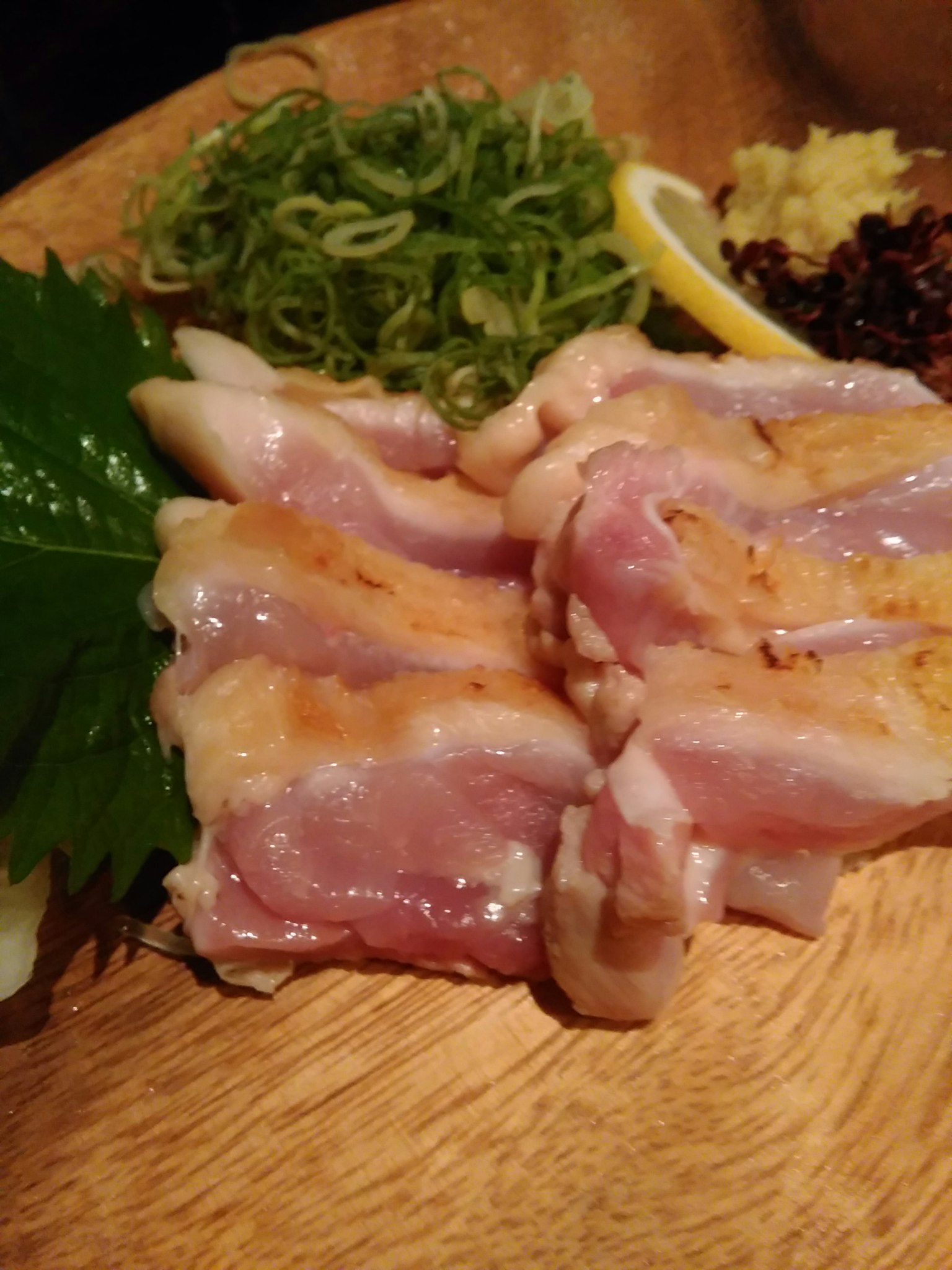 新鲜切片鸡肉放在木盘上，旁边有青葱和柠檬