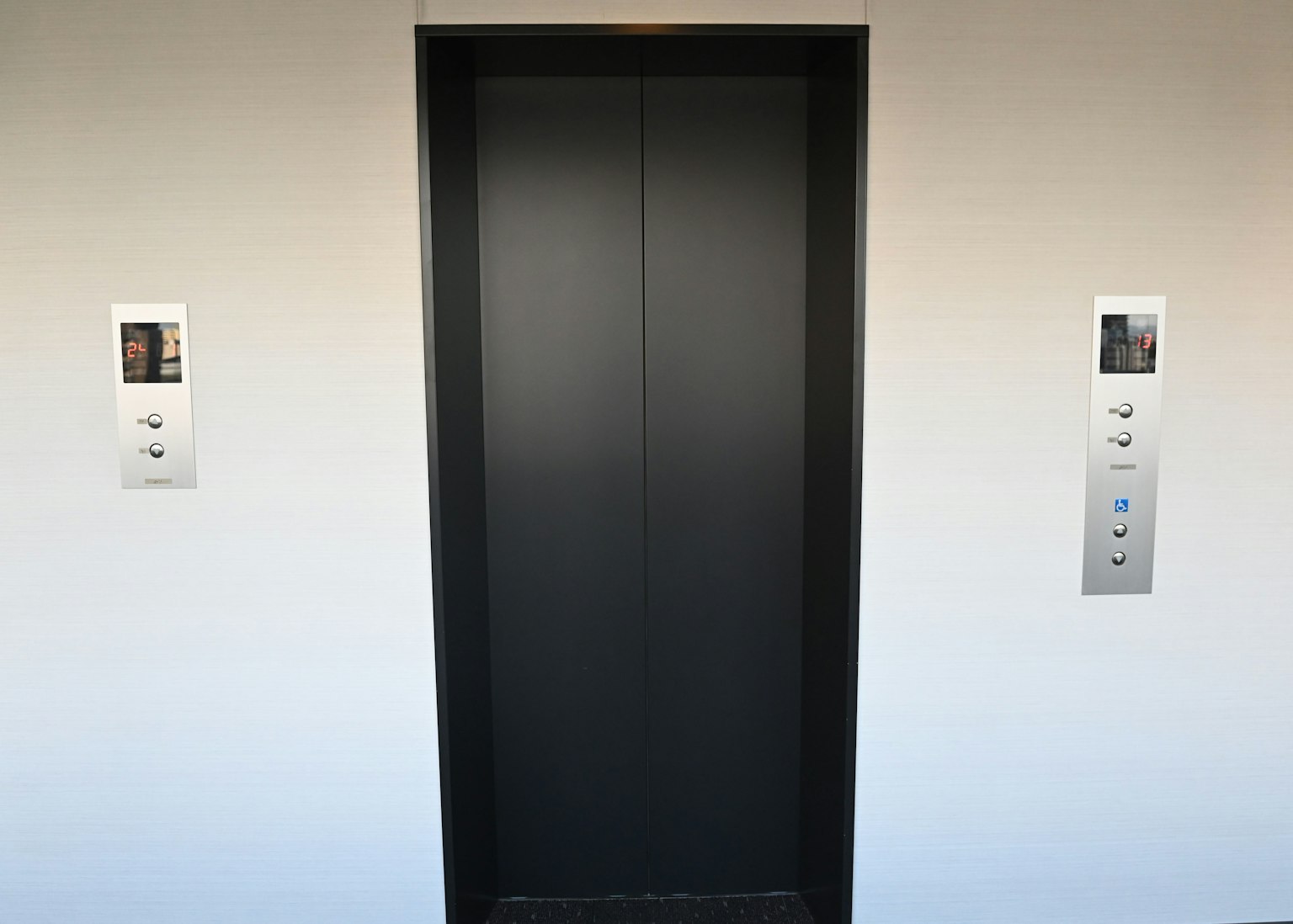 Puertas de ascensor negras con paneles de botones a cada lado