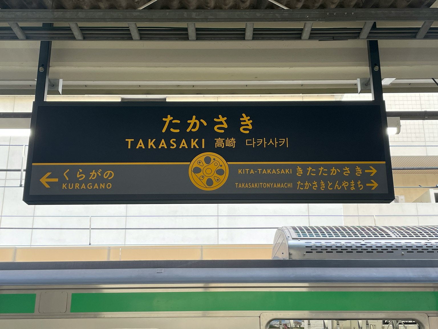 Papan nama Stasiun Takasaki menampilkan nama dalam bahasa Jepang dan Inggris
