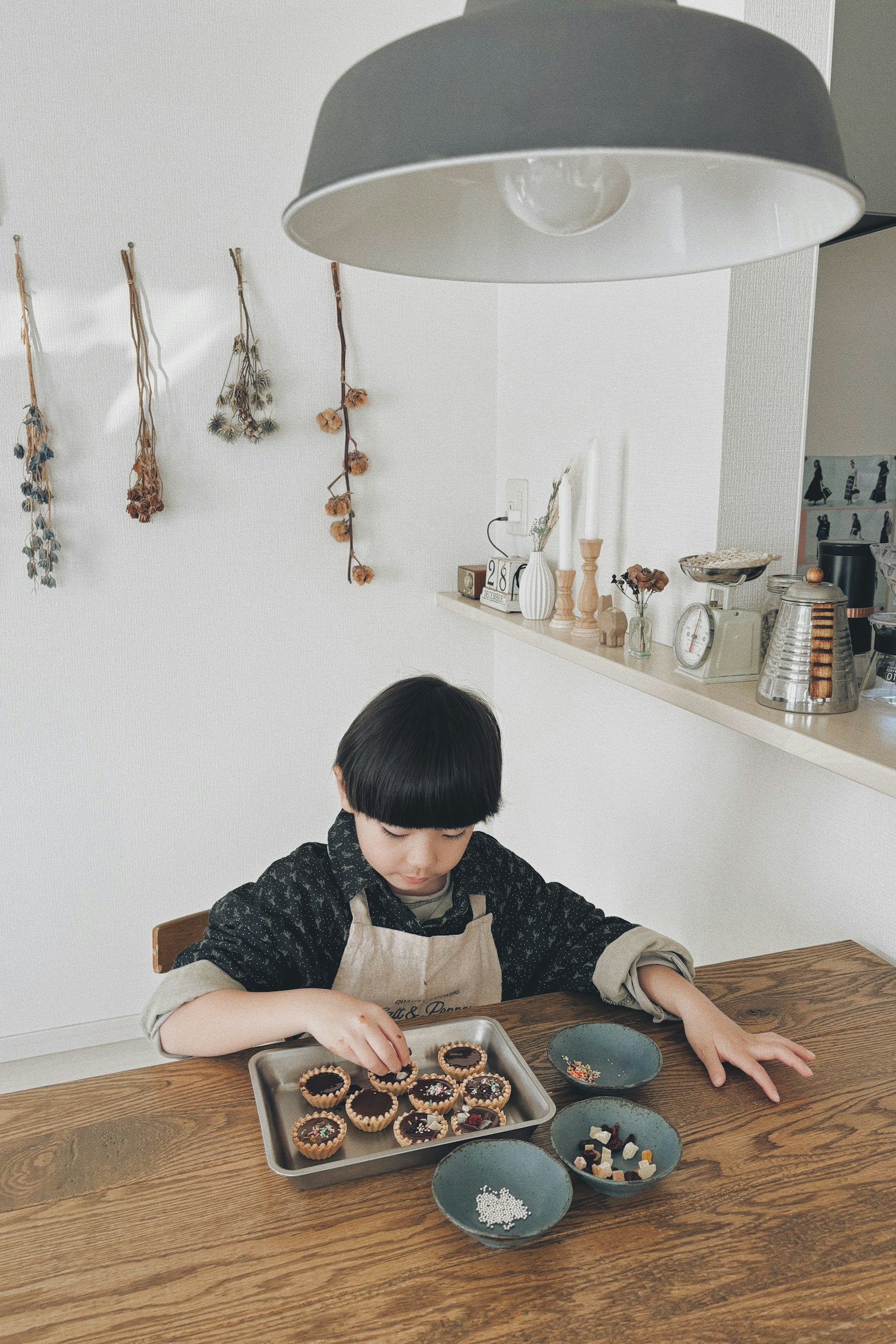 Niño horneando pasteles en una mesa de madera cocina brillante con utensilios y decoraciones
