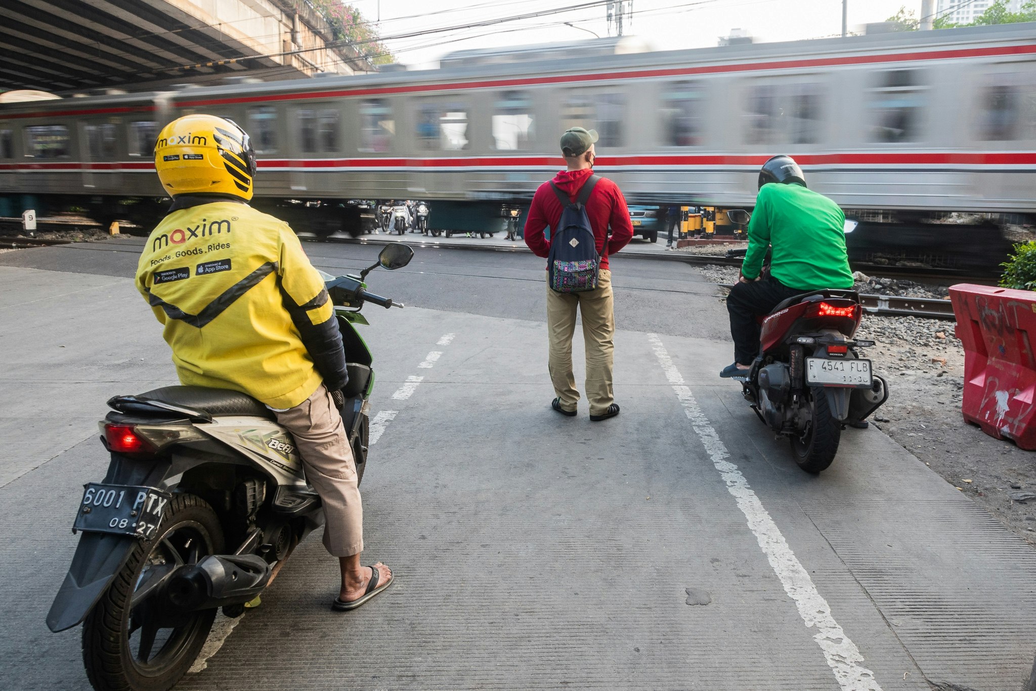 駅前の線路沿いで停車するバイクと人々