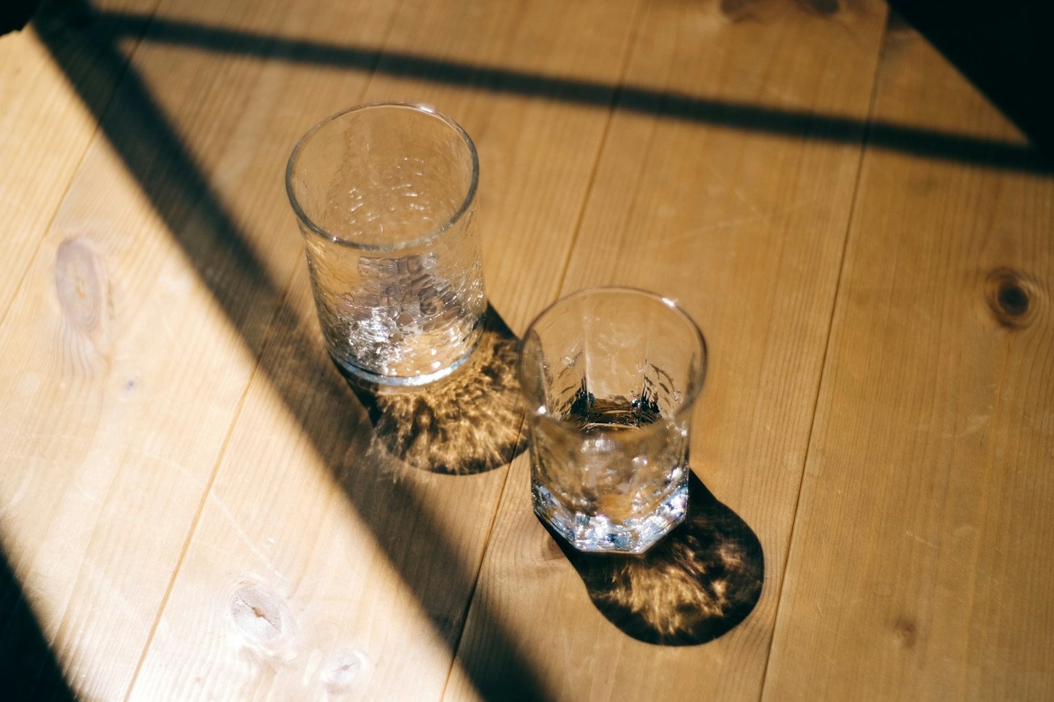 Deux verres sur une table en bois avec des ombres