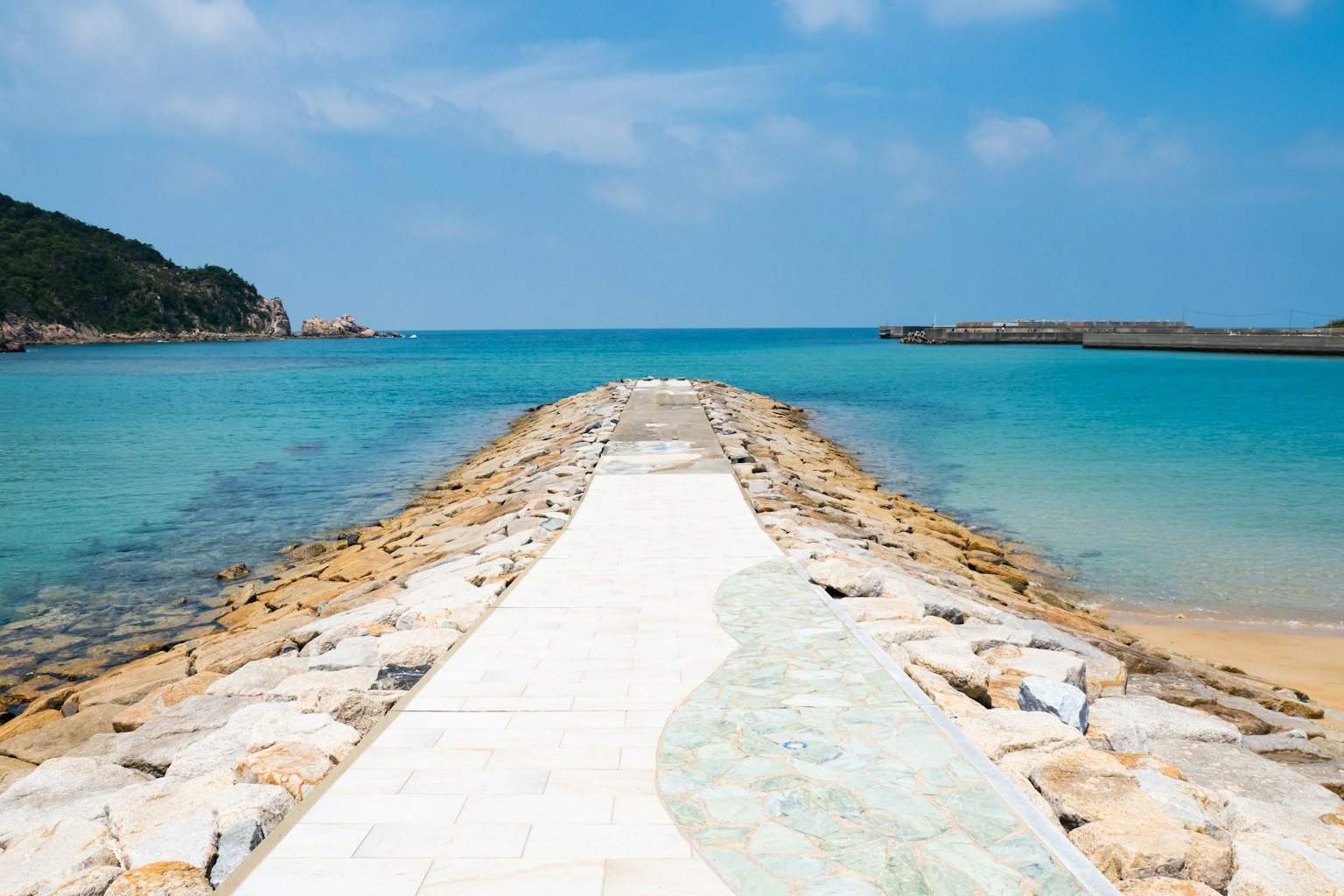 Schöne Küstenansicht mit einem weißen Weg, der zum blauen Meer führt