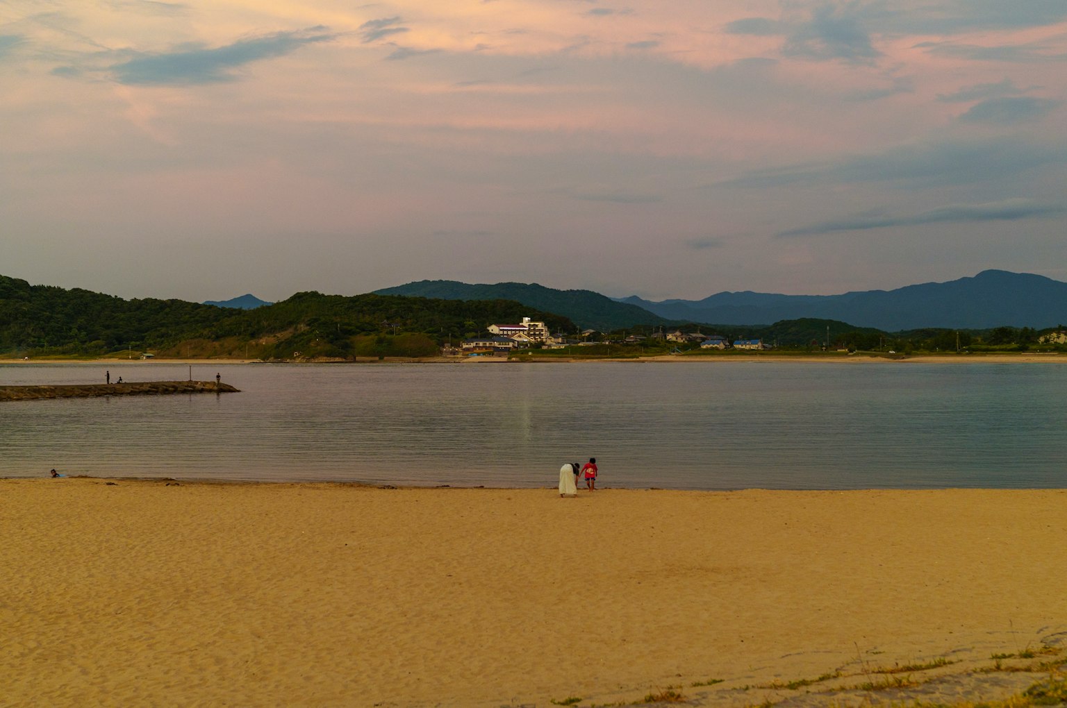 Scène de plage sereine avec des eaux calmes et des montagnes au loin