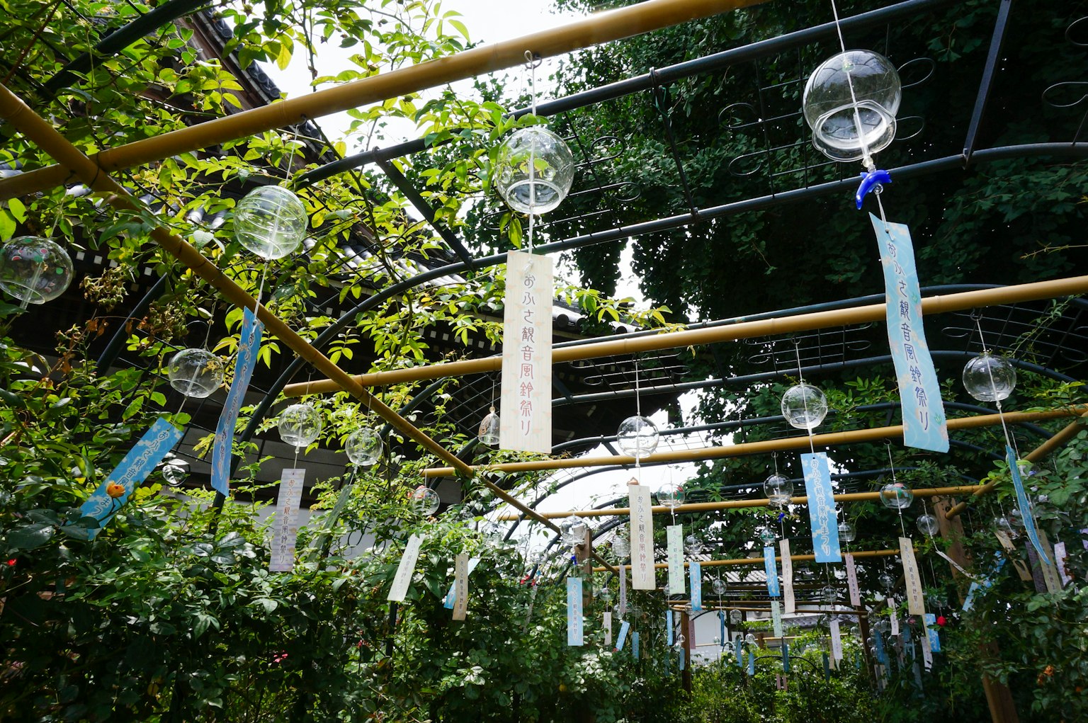Campane a vento e decorazioni tanzaku appese sotto una struttura di bambù
