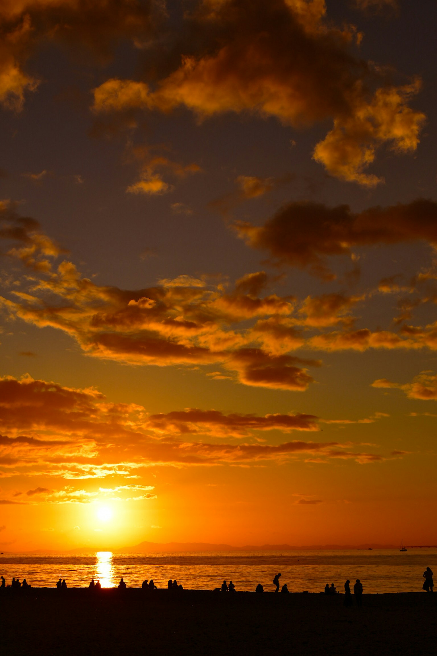 夕日が海に沈む美しい風景とシルエットの人々