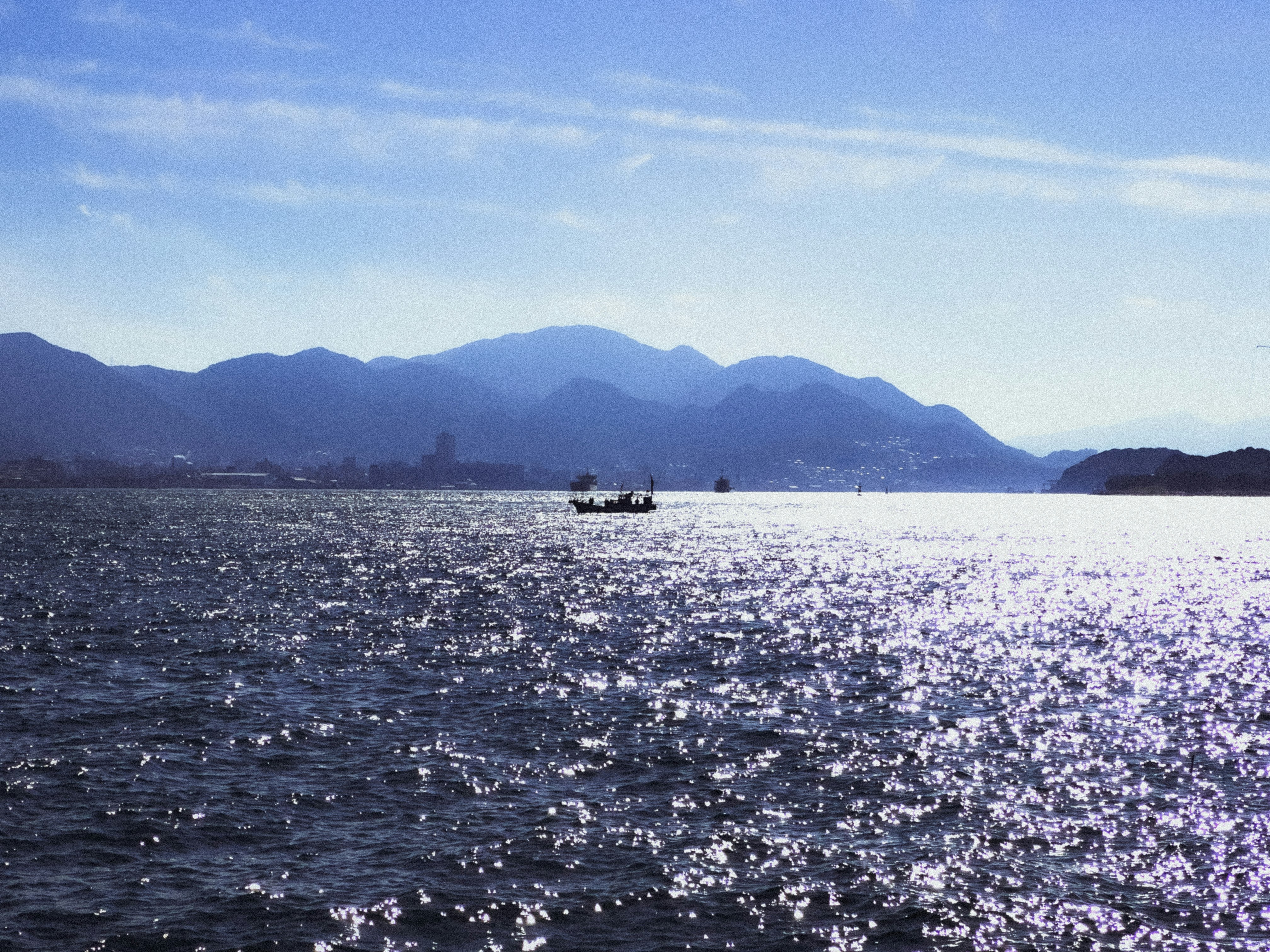 海面にきらめく波と遠くの山並みの風景
