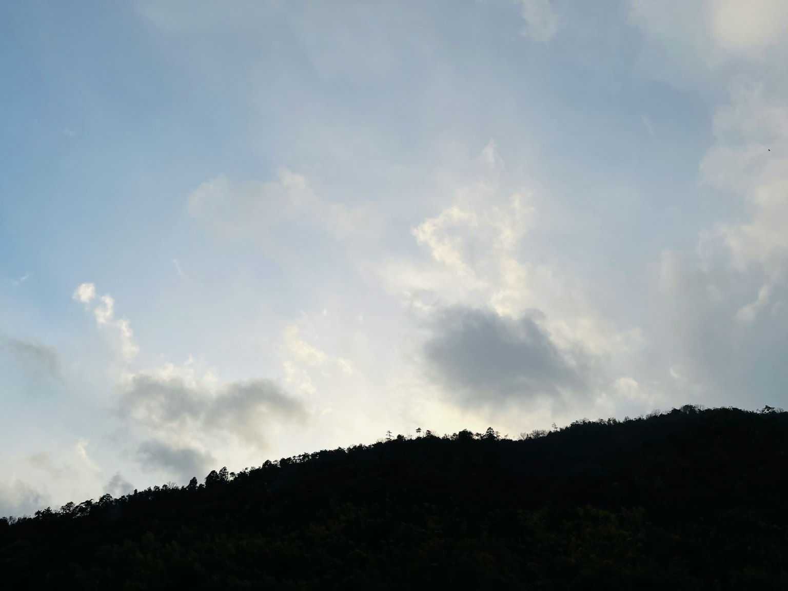 푸른 하늘과 구름을 배경으로 한 산의 실루엣
