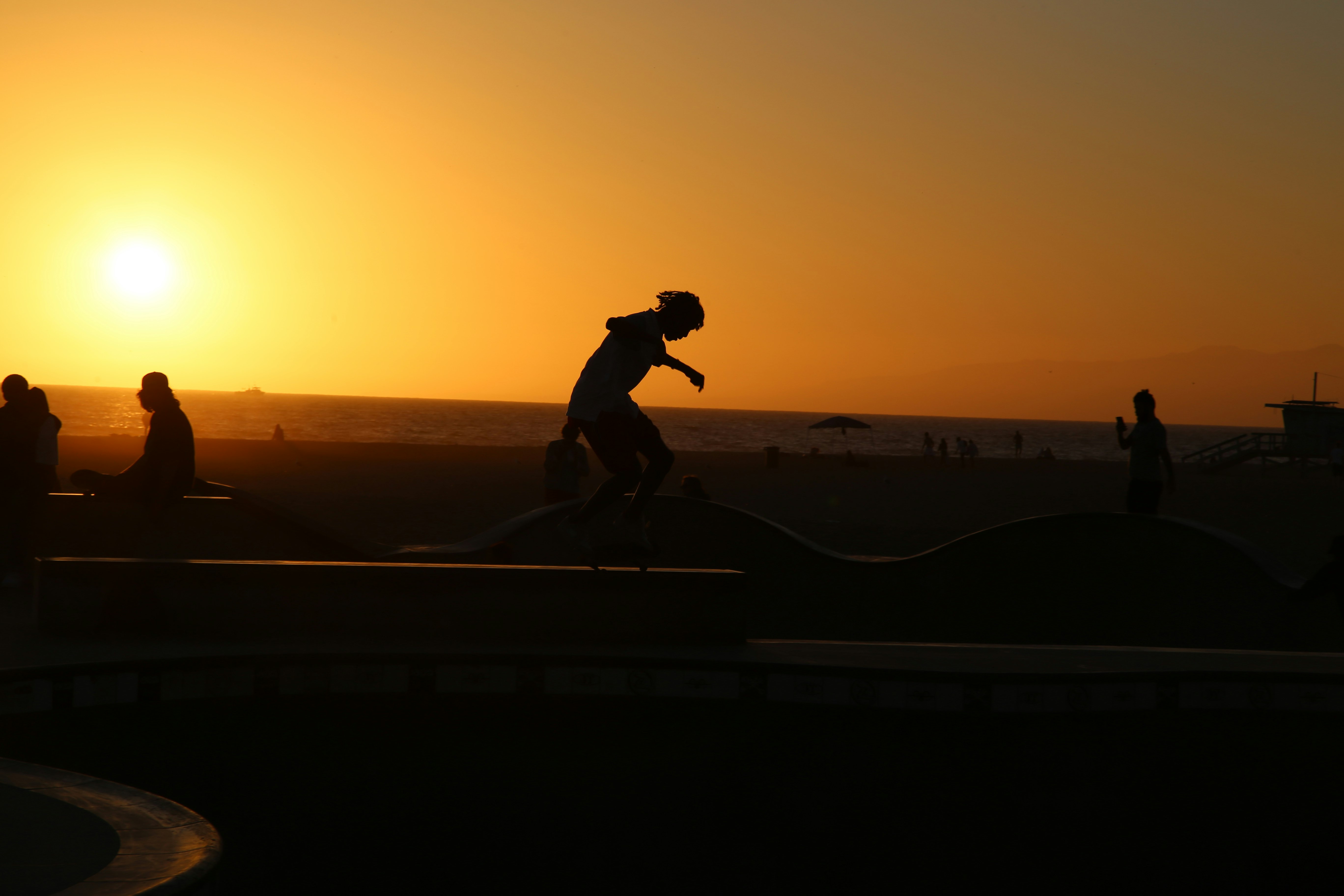夕日に照らされたスケボーのシルエットが広がる海辺の遊歩道