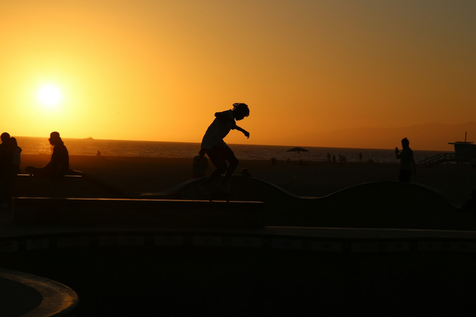 Silhouette of a young skateboarder against a sunset background