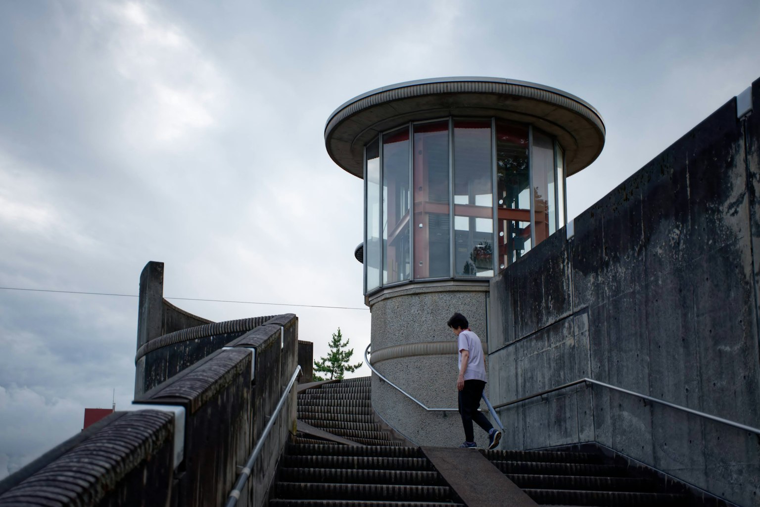 Person walking up stairs towards a modern observation tower