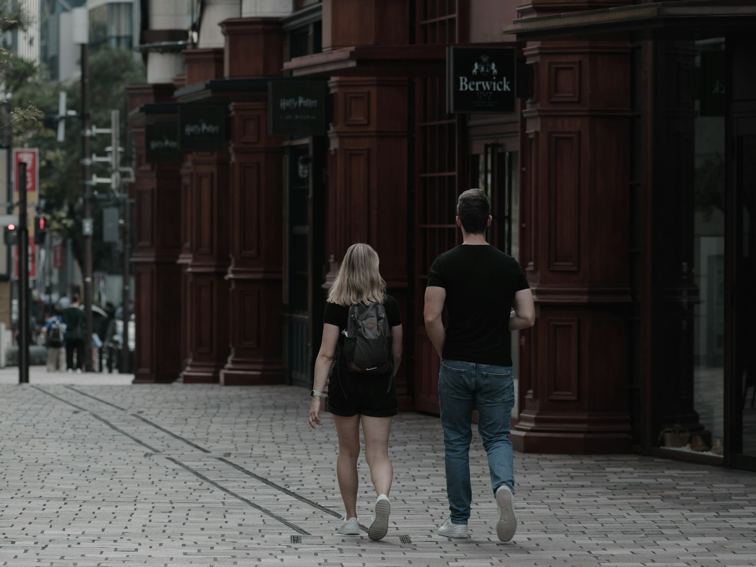 A casual couple walking down a city street lined with shops