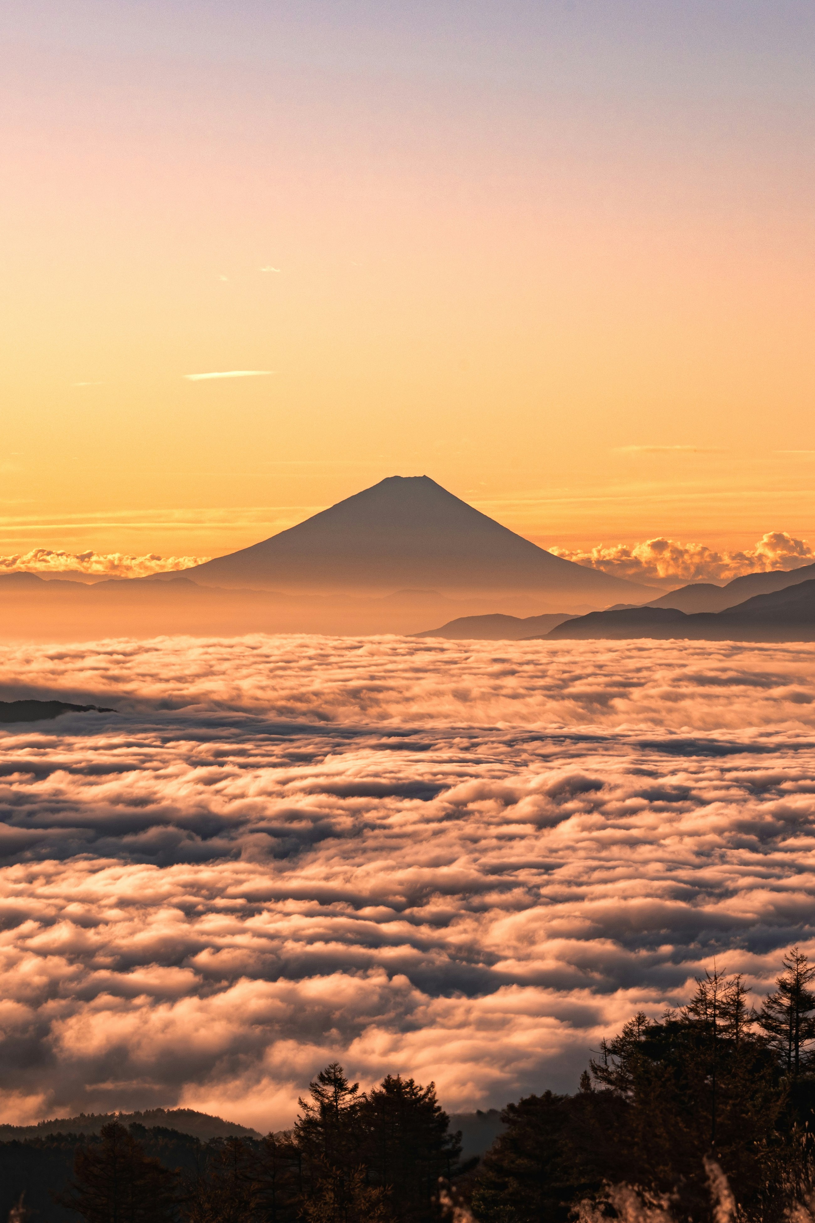 雲海の上にそびえる山と夕焼けの空
