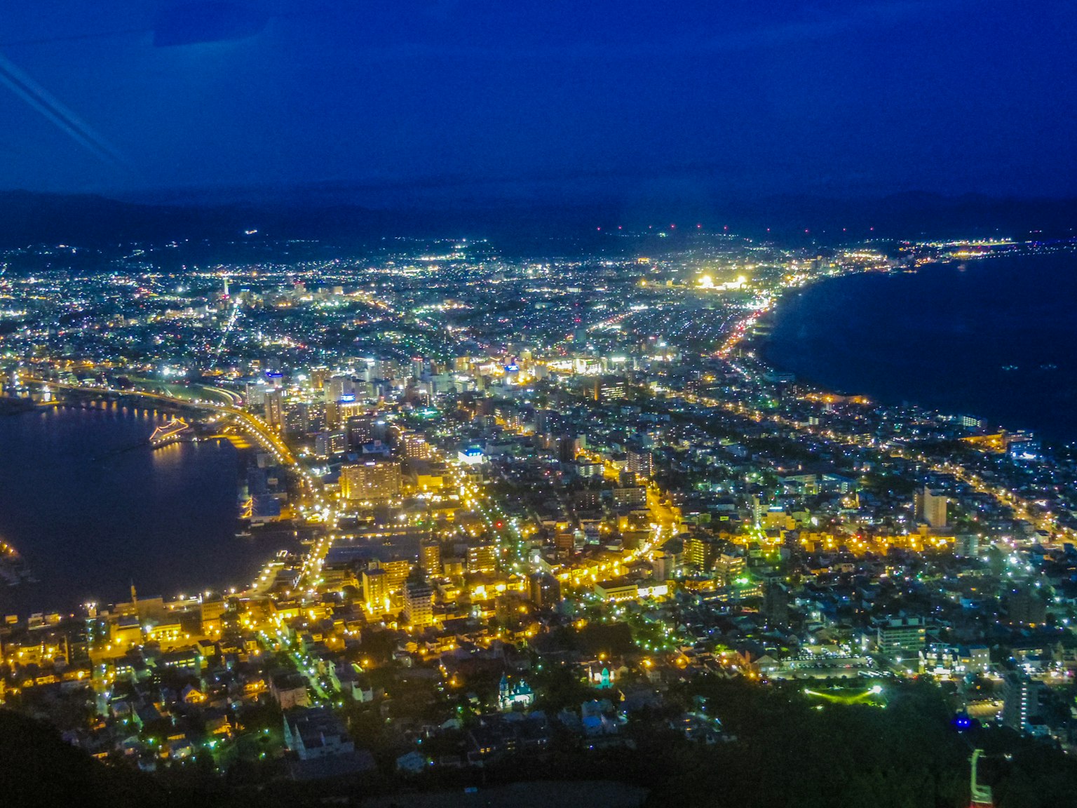 Vue aérienne d'une ville portuaire animée la nuit avec des lampadaires brillants et une mer scintillante