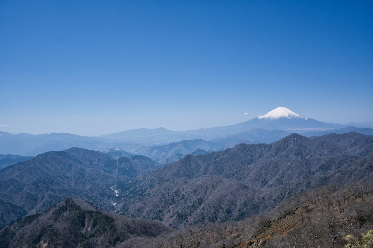Mountains under a clear blue sky with snow-capped Mount Fuji