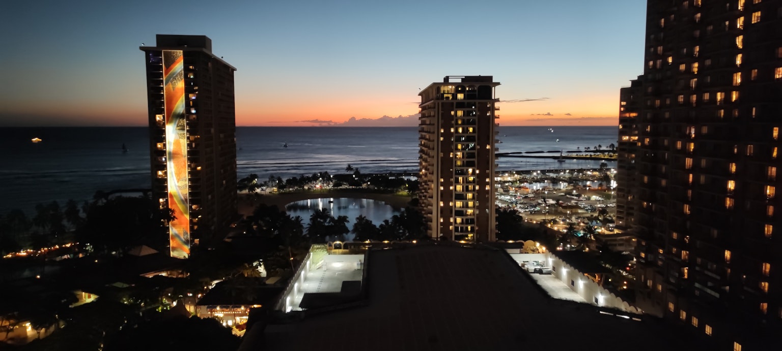 Khung cảnh bờ biển Hawaii vào lúc hoàng hôn với các tòa nhà sáng đèn