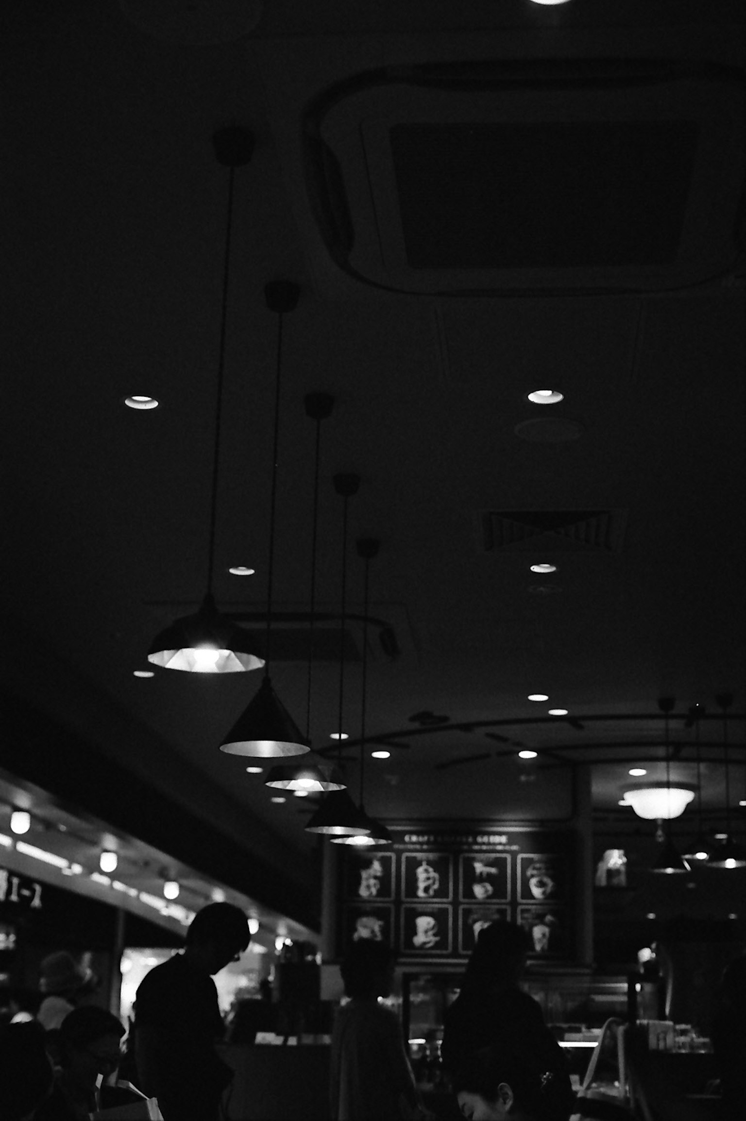 Silhouette di un interno di caffè poco illuminato con lampade sospese
