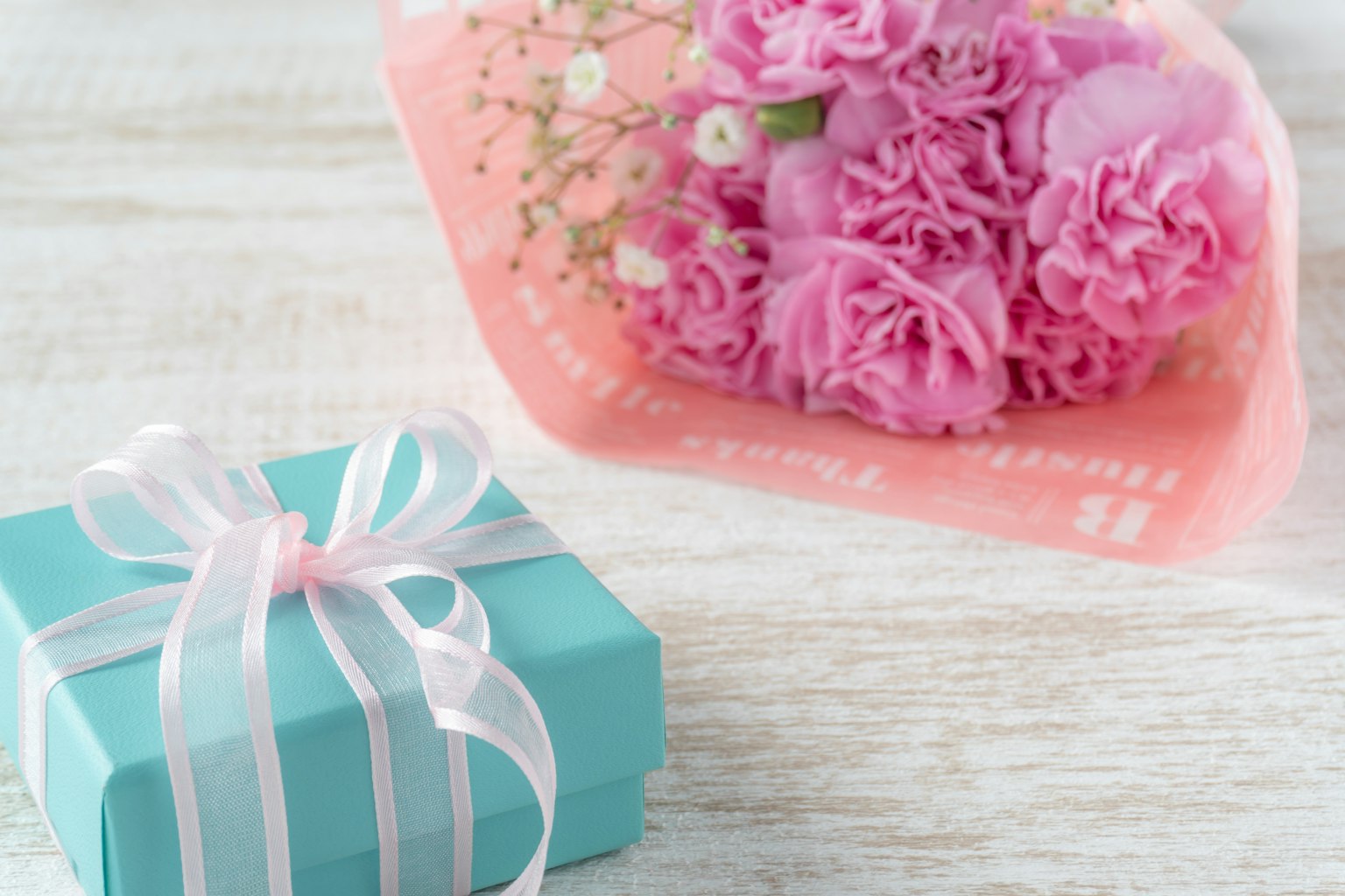 Schöne Anordnung eines rosa Blumenstraußes und einer blauen Geschenkbox