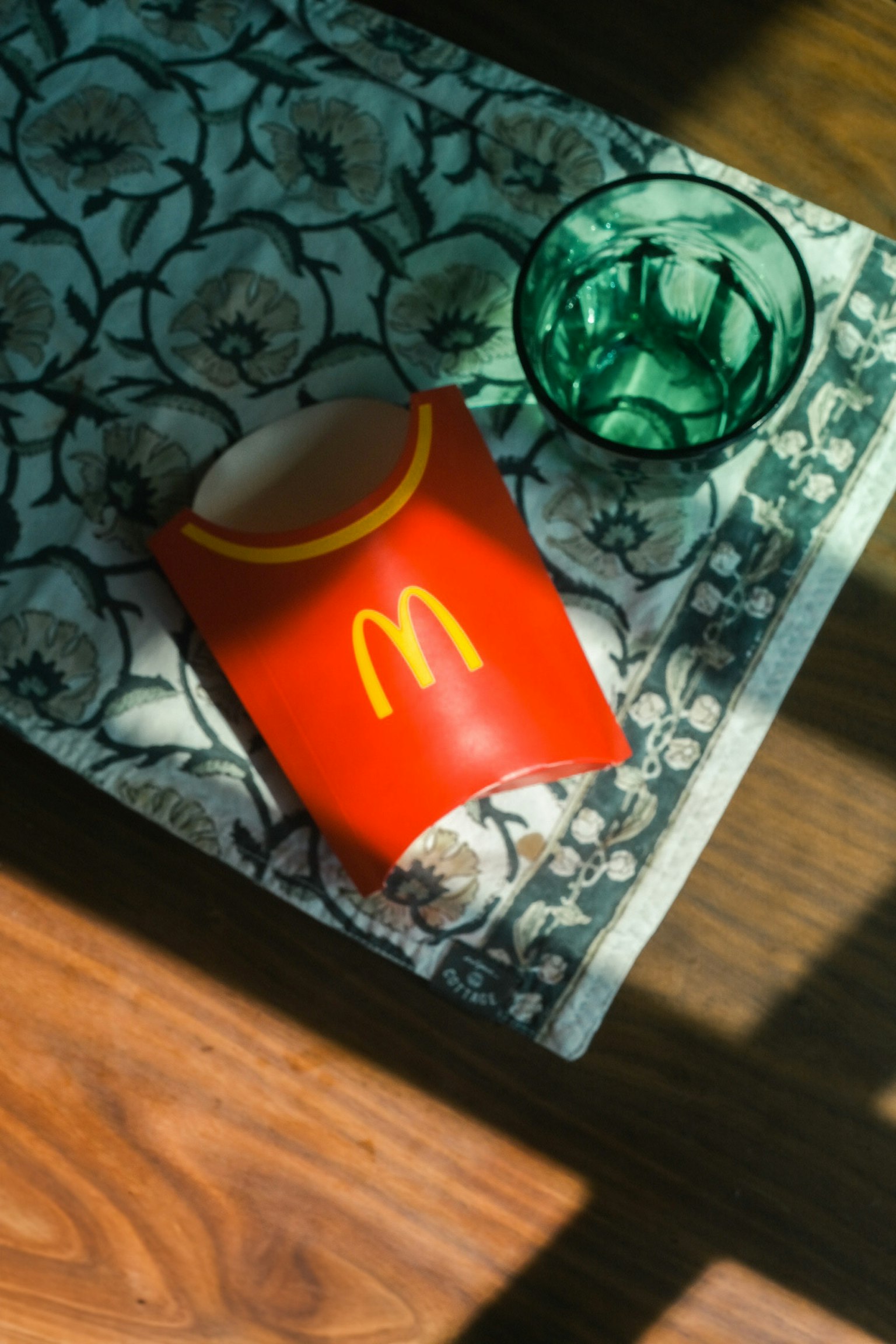 Contenitore di patatine McDonald's rosso e bicchiere verde su una tovaglia a motivi