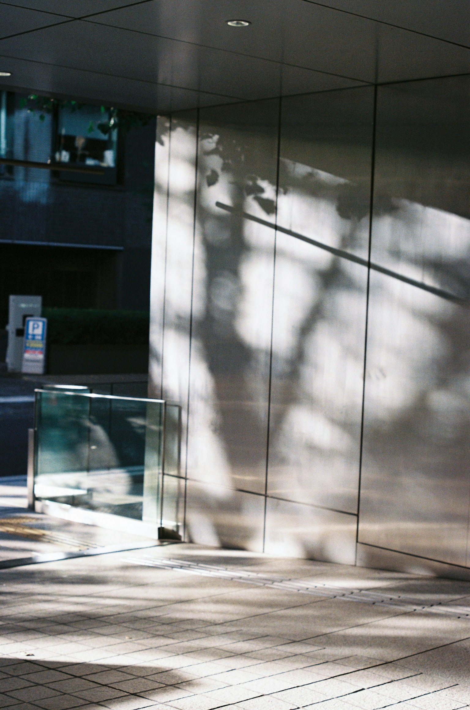 Ombres à l'entrée d'un bâtiment moderne avec des surfaces réfléchissantes