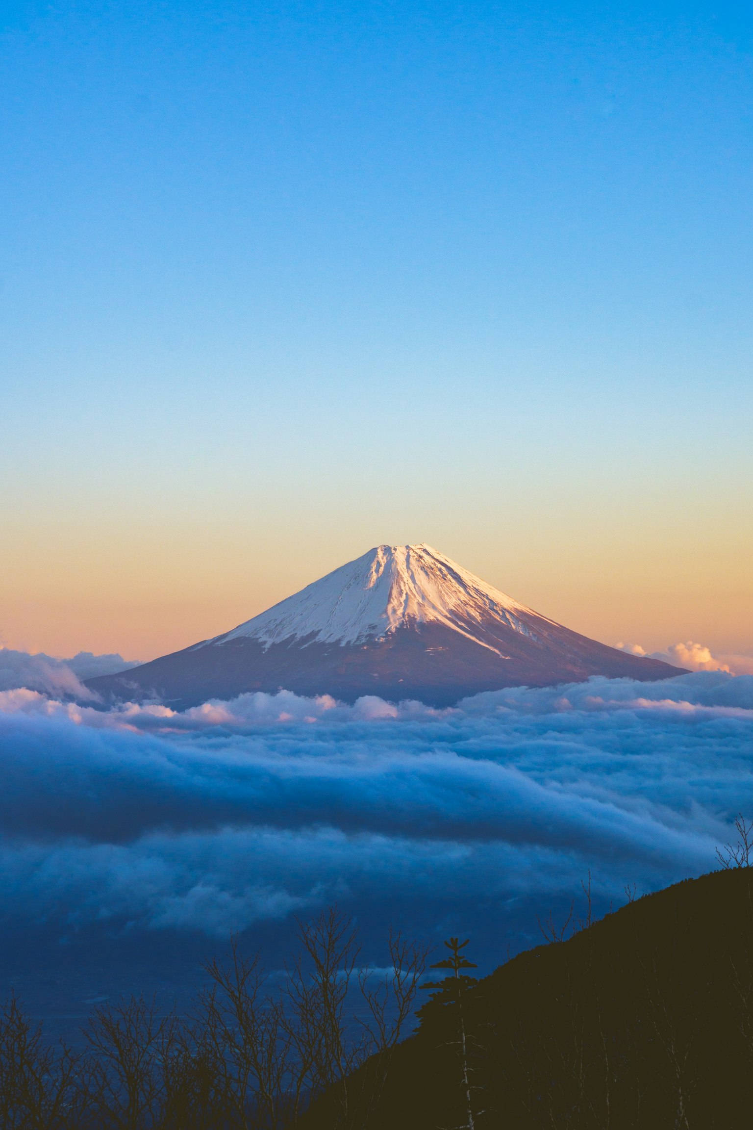 Snow-capped Mount Fuji surrounded by blue sky and clouds