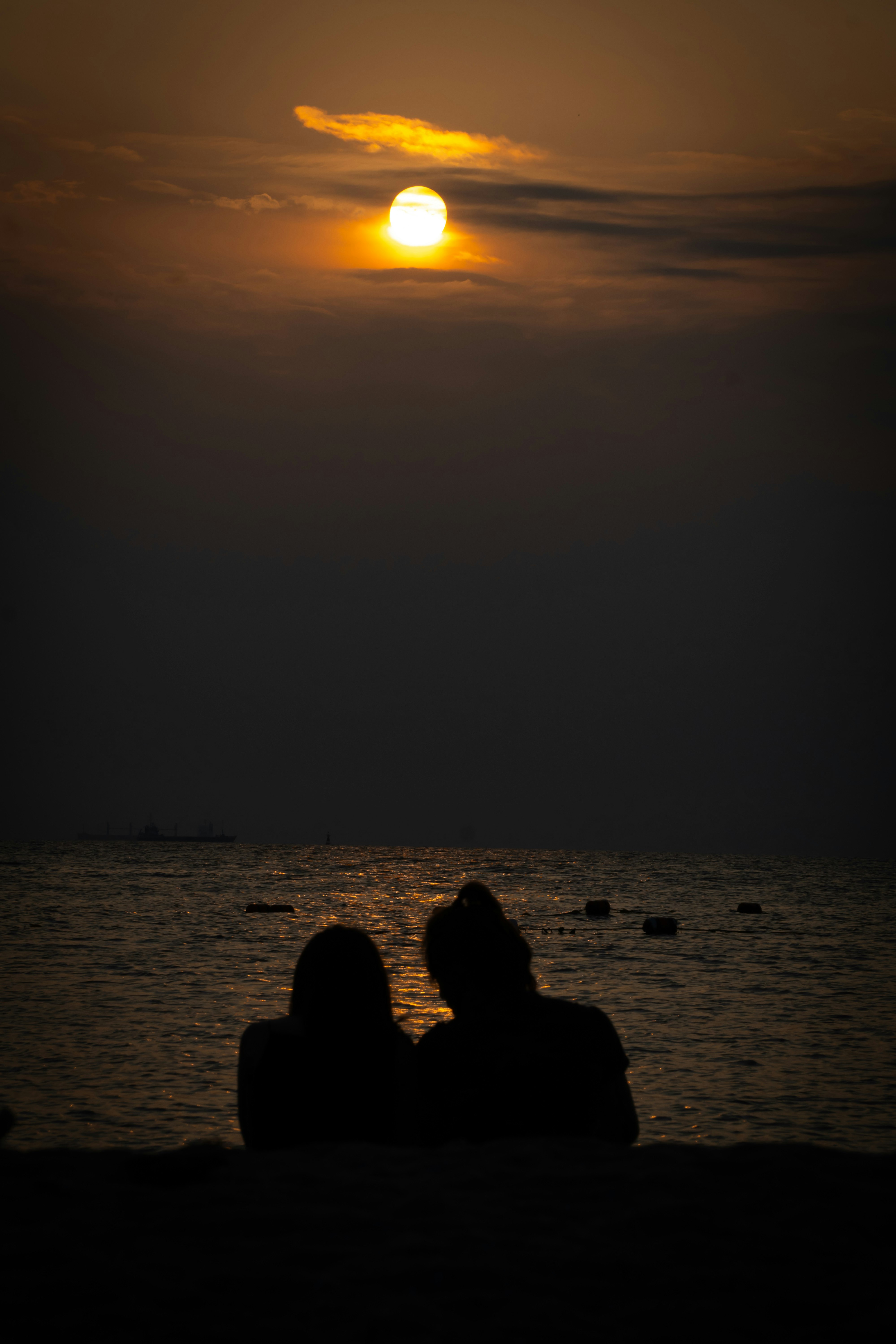 夕日に照らされる海辺で寄り添うシルエット