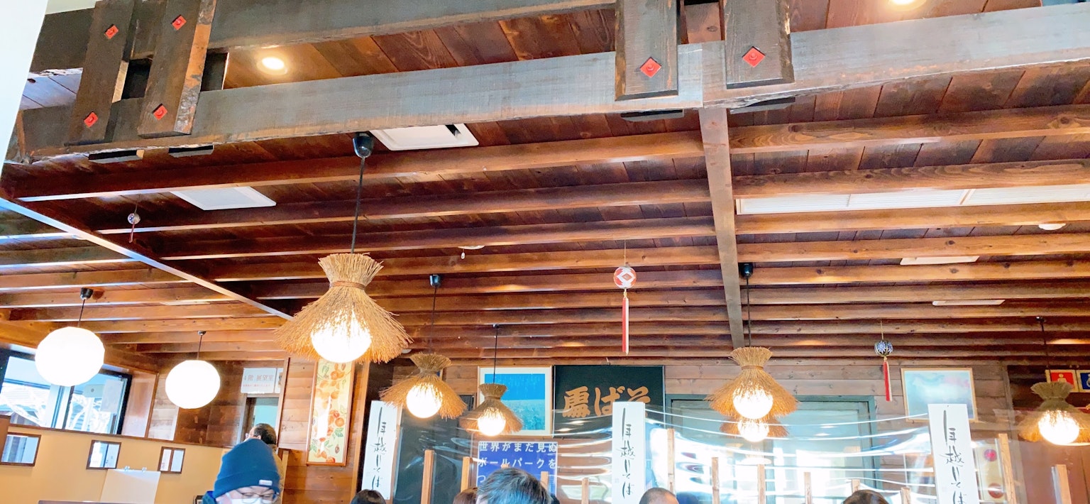 Interior de un restaurante japonés con vigas de madera y iluminación tradicional