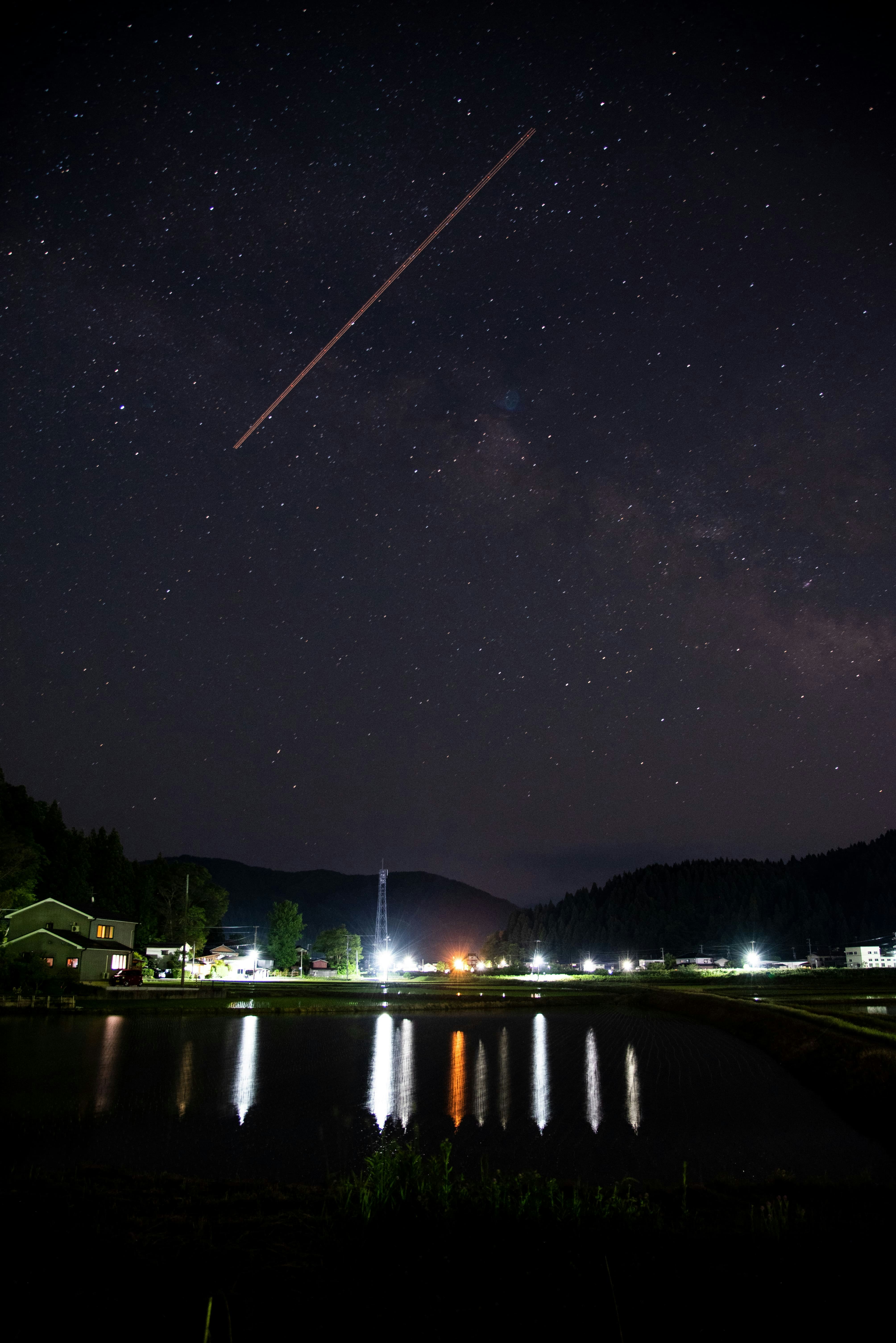 夜の湖畔に映る街の灯りと星空