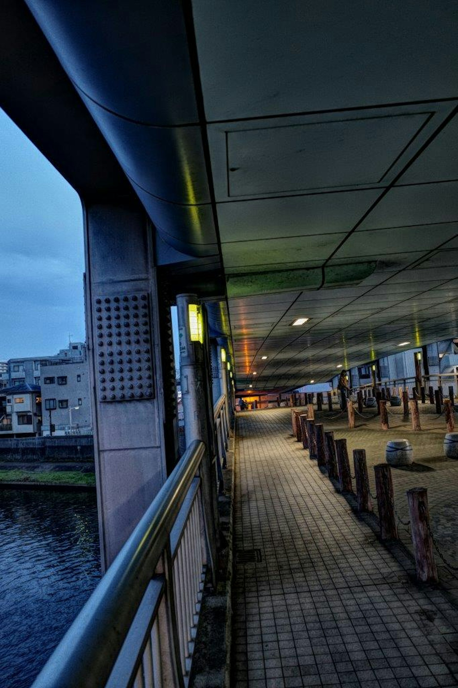 Passage couvert le long d'une rivière avec des lampadaires et une vue sur la ville