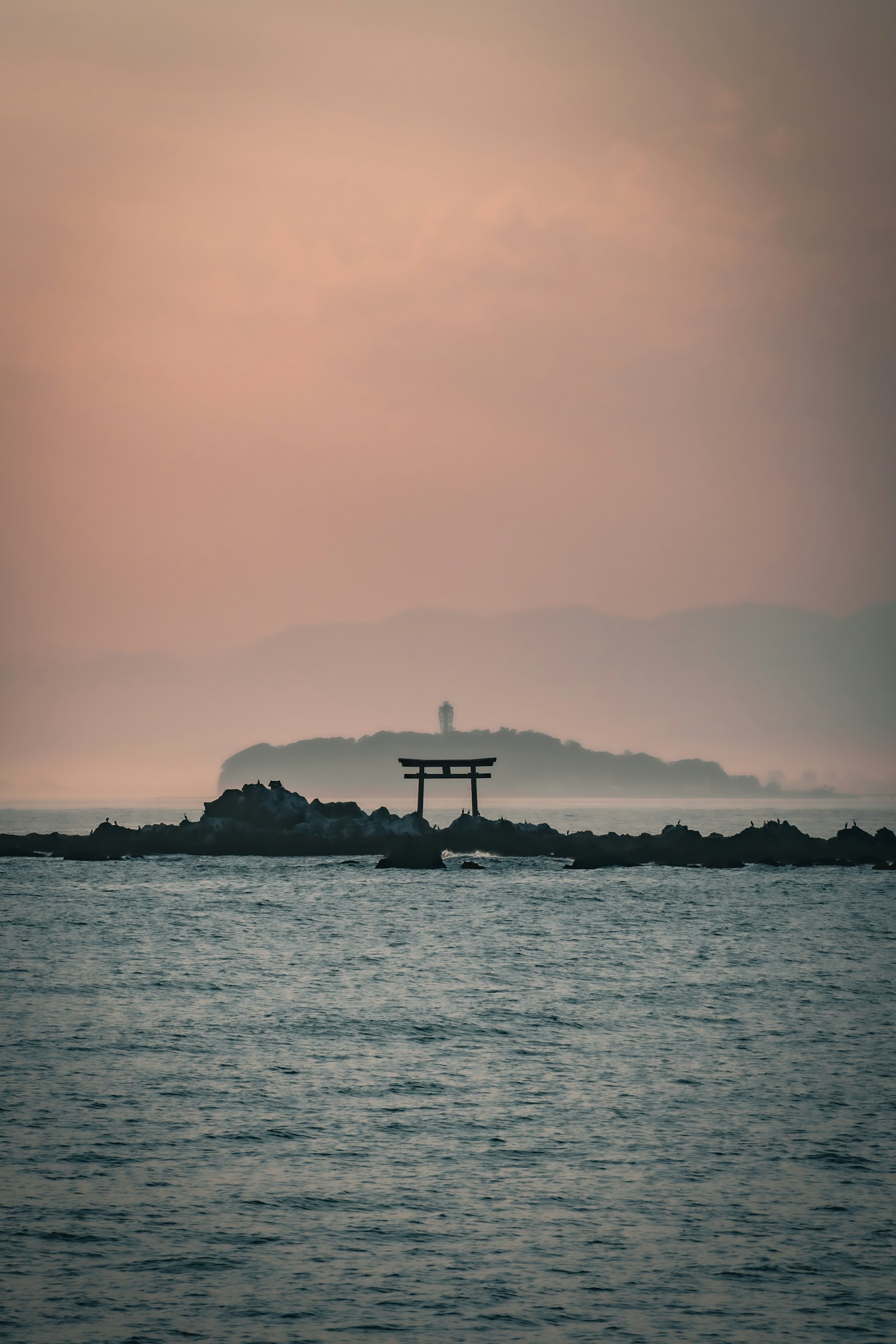 Torii บนผิวน้ำพร้อมกับประภาคารในระยะไกล