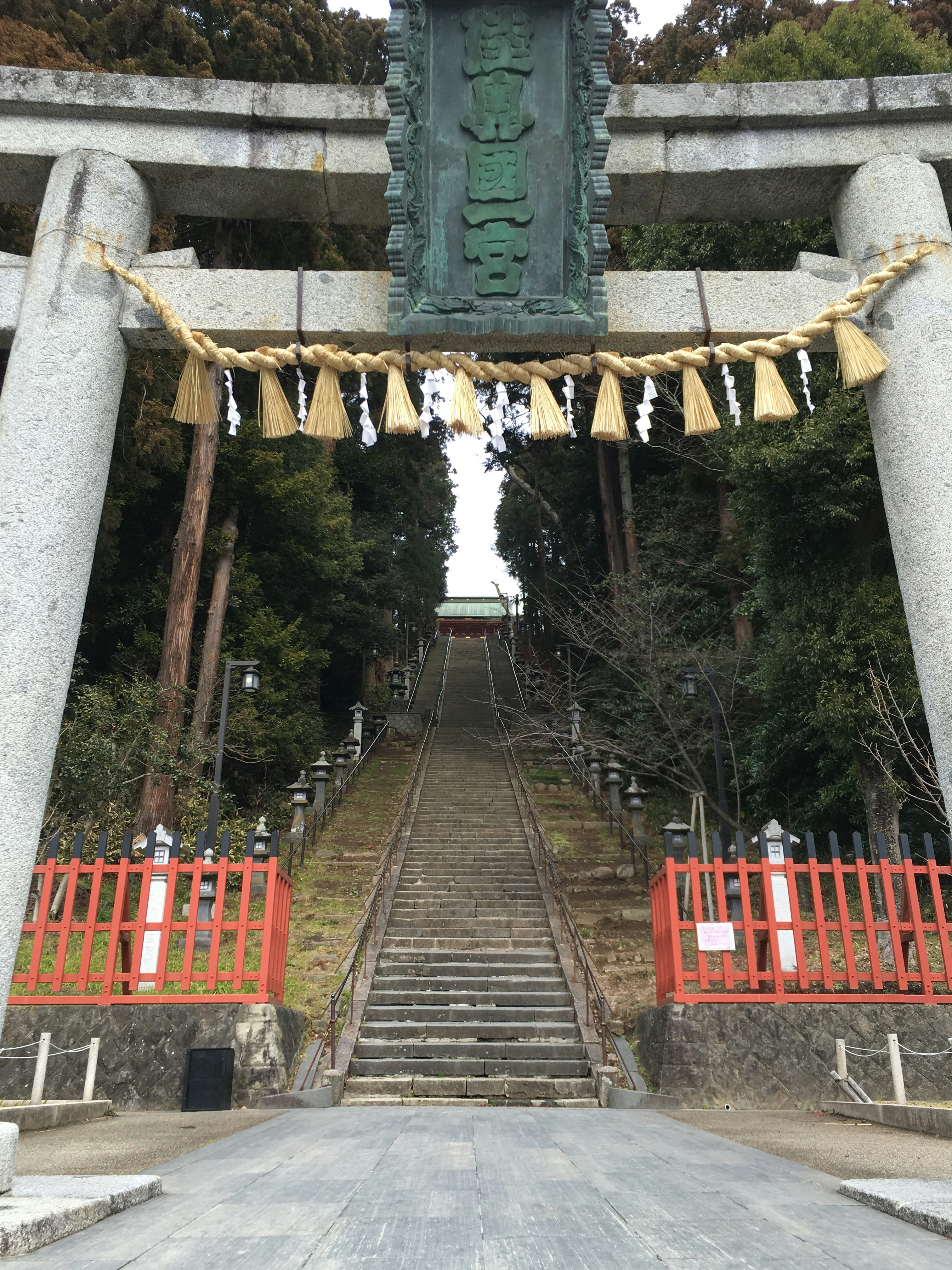 Gerbang torii dengan pagar merah dan tangga batu menuju bukit