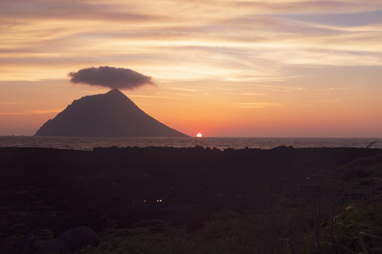 日落時火山的輪廓與雲朵