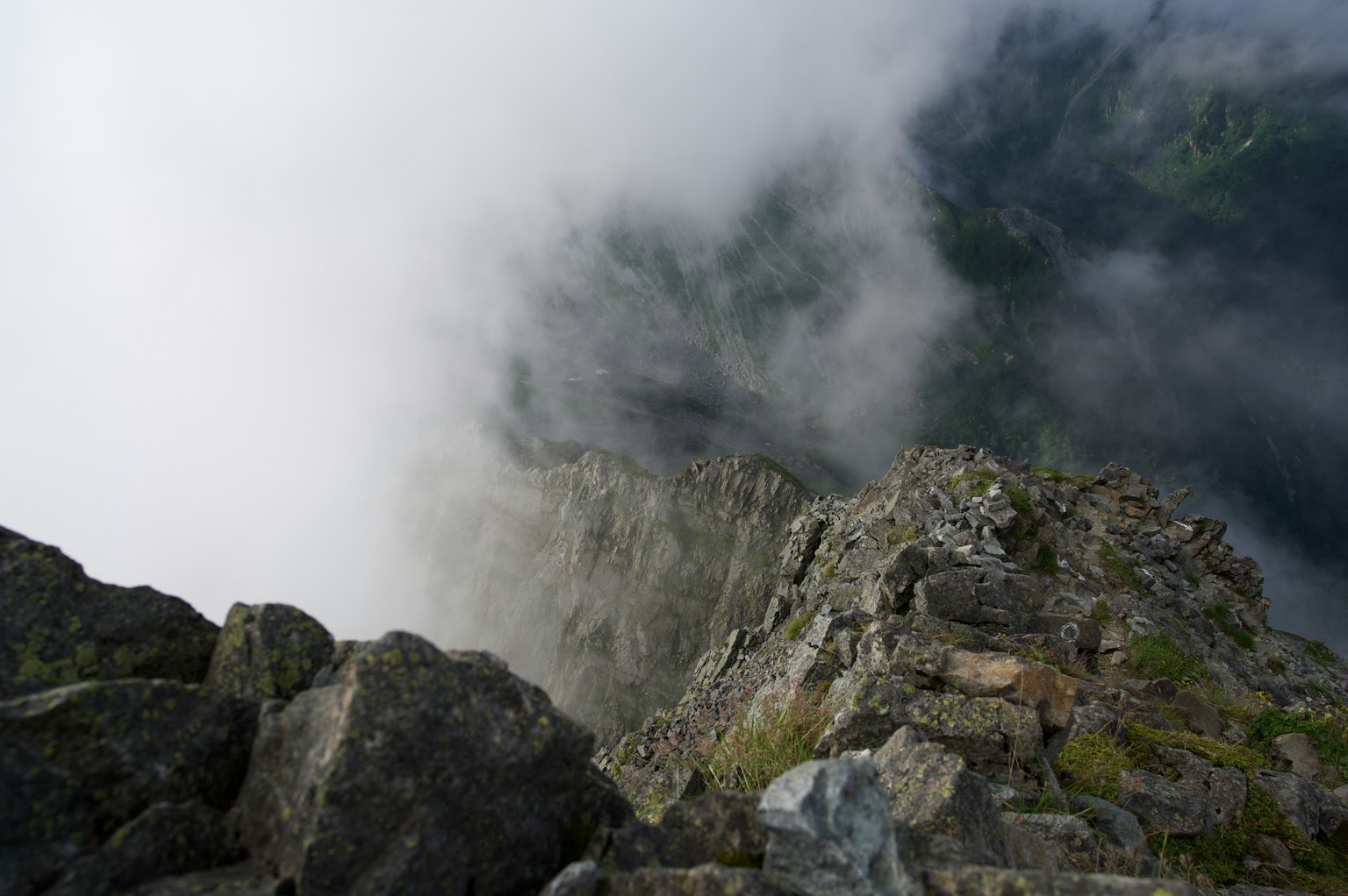 View from the mountain peak with fog covering the landscape and visible rocky outcrop
