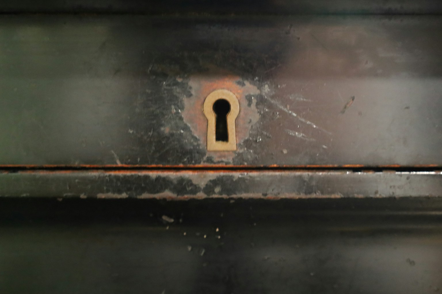 Close-up of a rusty keyhole on a dark metal surface