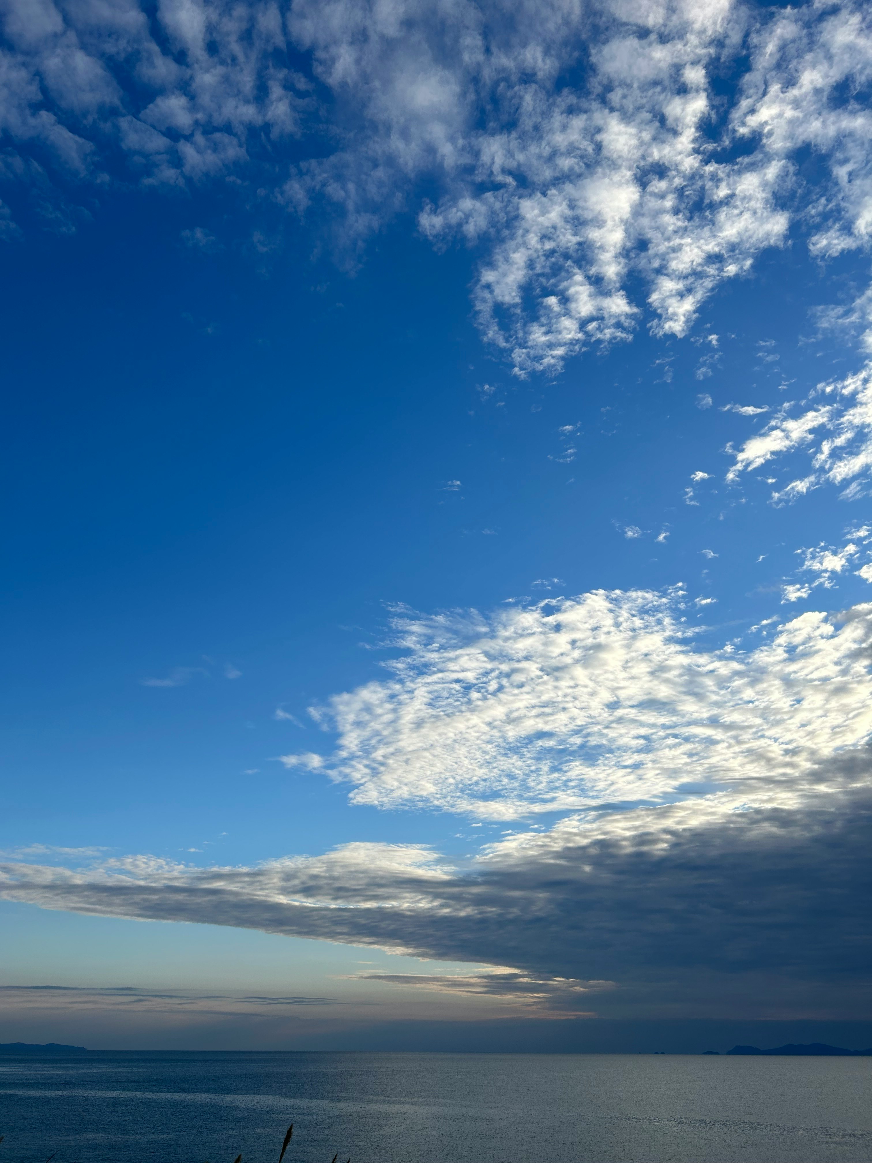 藍天與散落雲層下的海景地平線