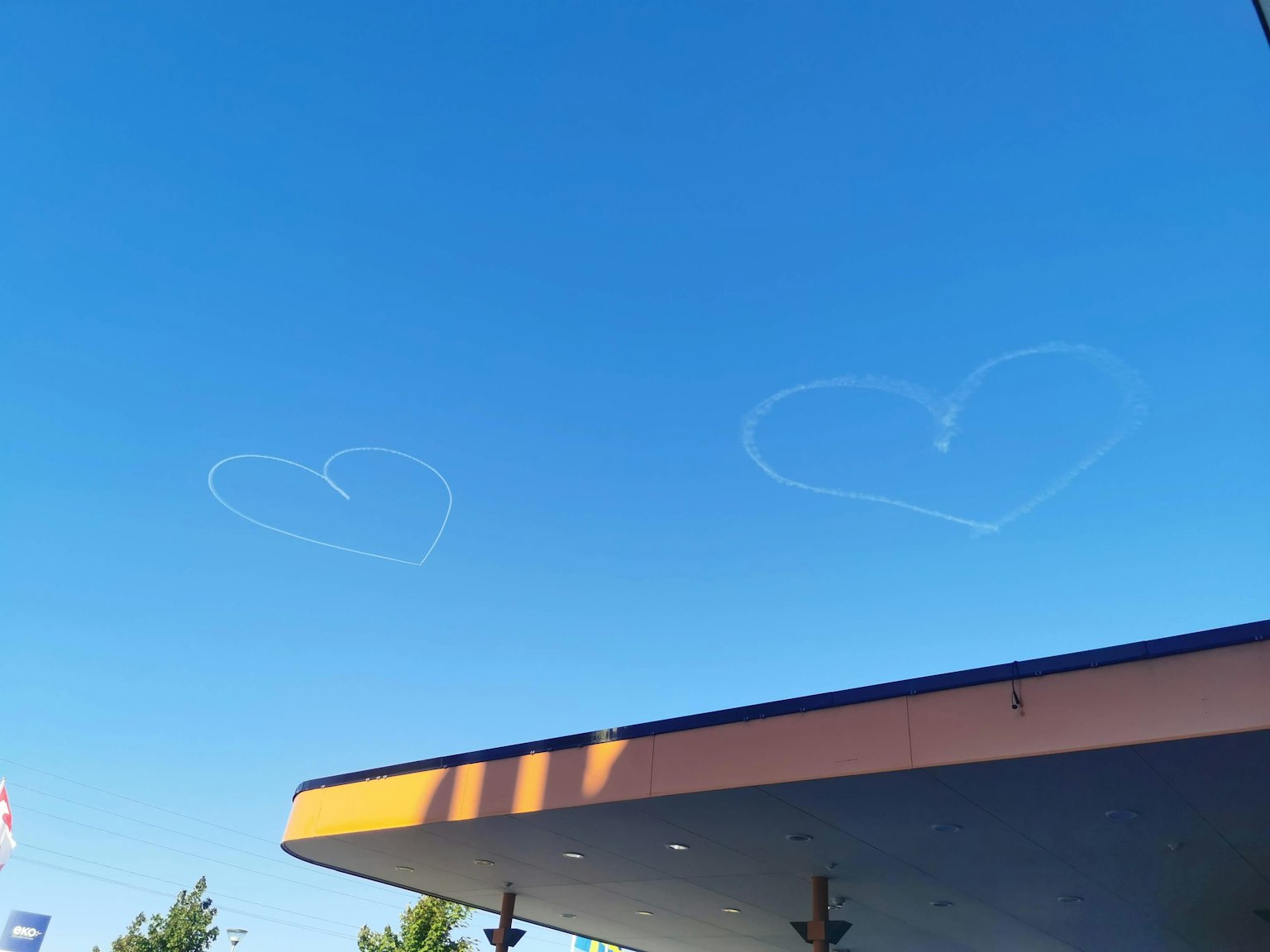 Scie di aereo a forma di cuore in un cielo blu con un tetto di edificio