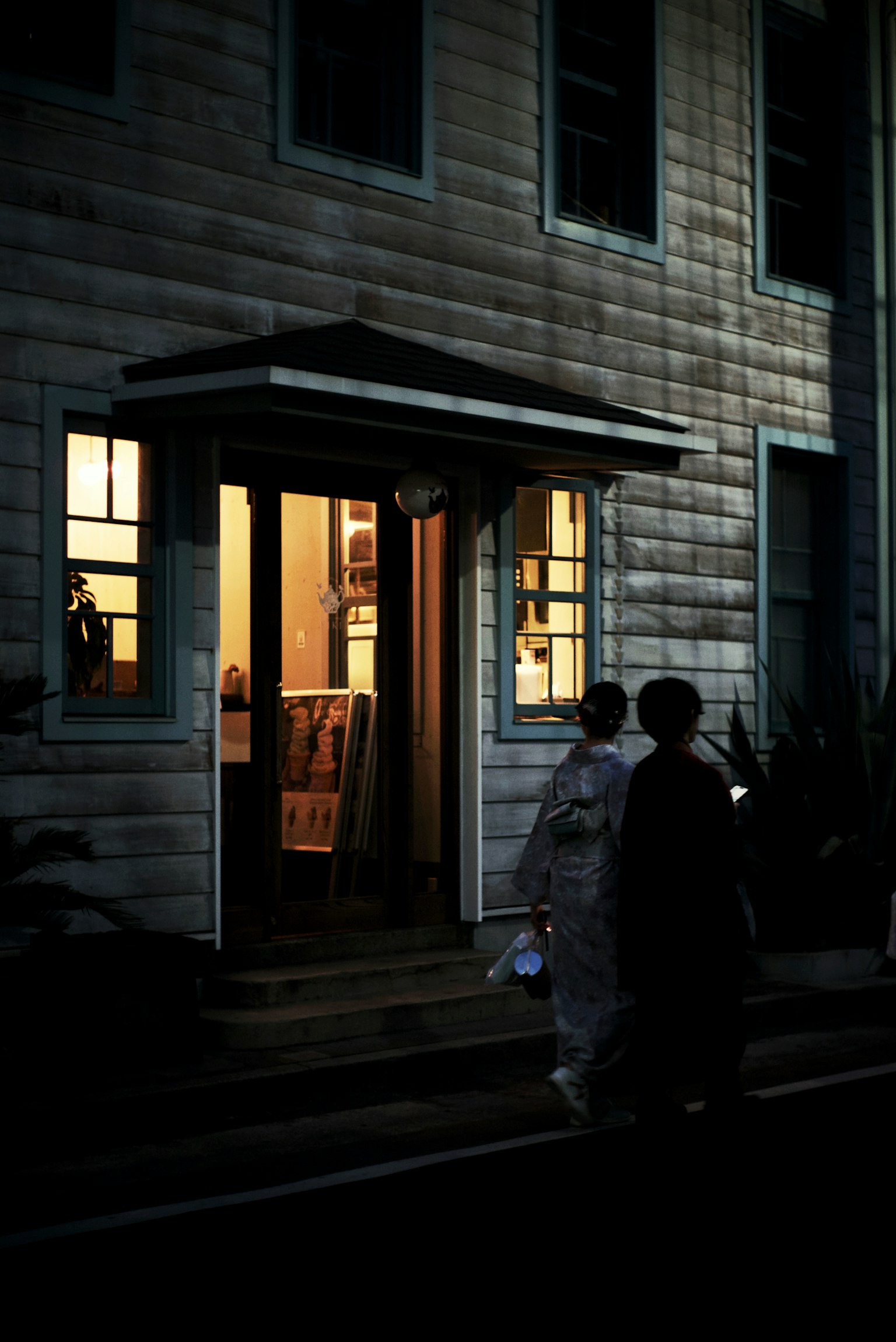 Des gens marchant devant une maison éclairée la nuit