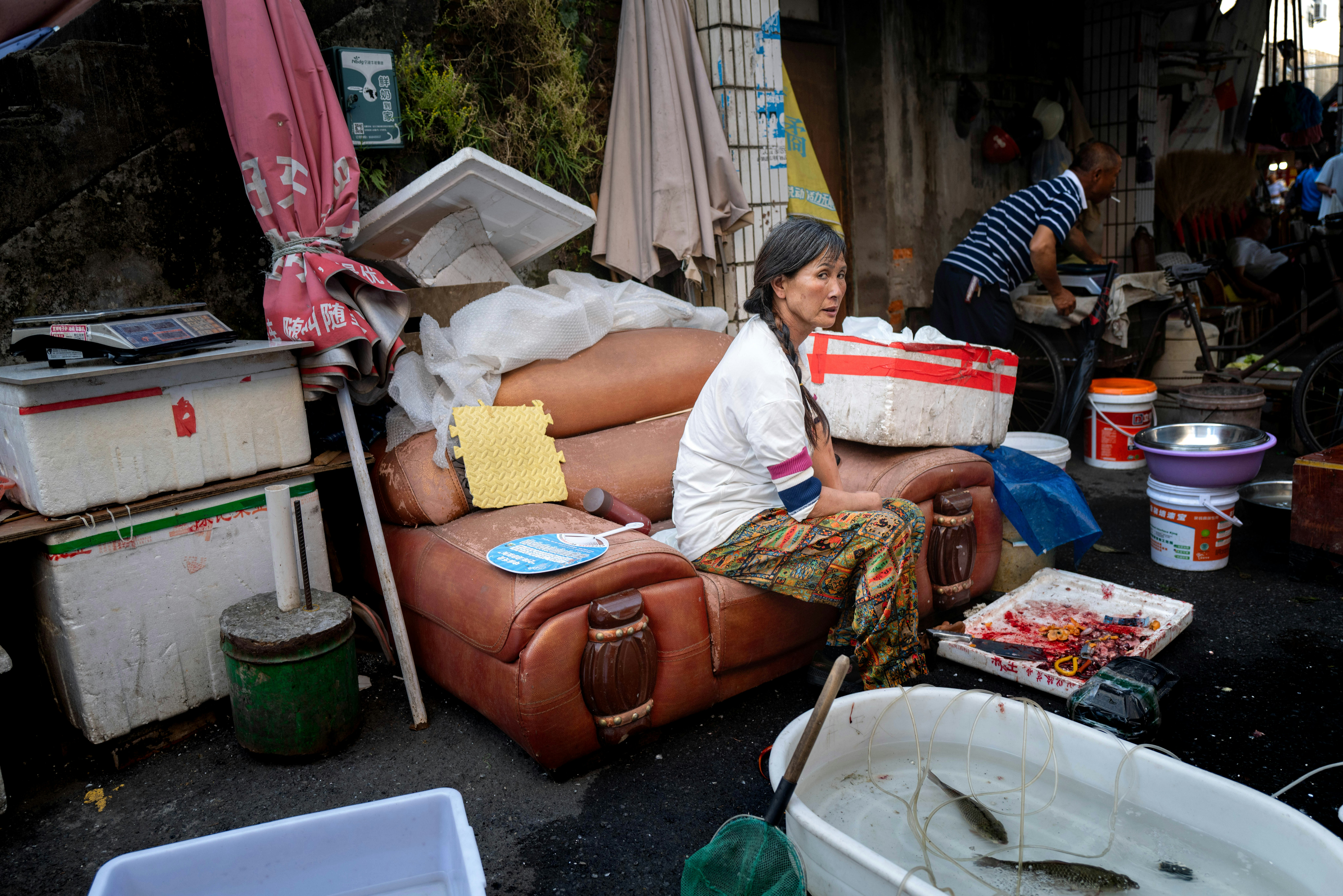 路地の屋外で椅子に座る女性のリサイクル作業風景