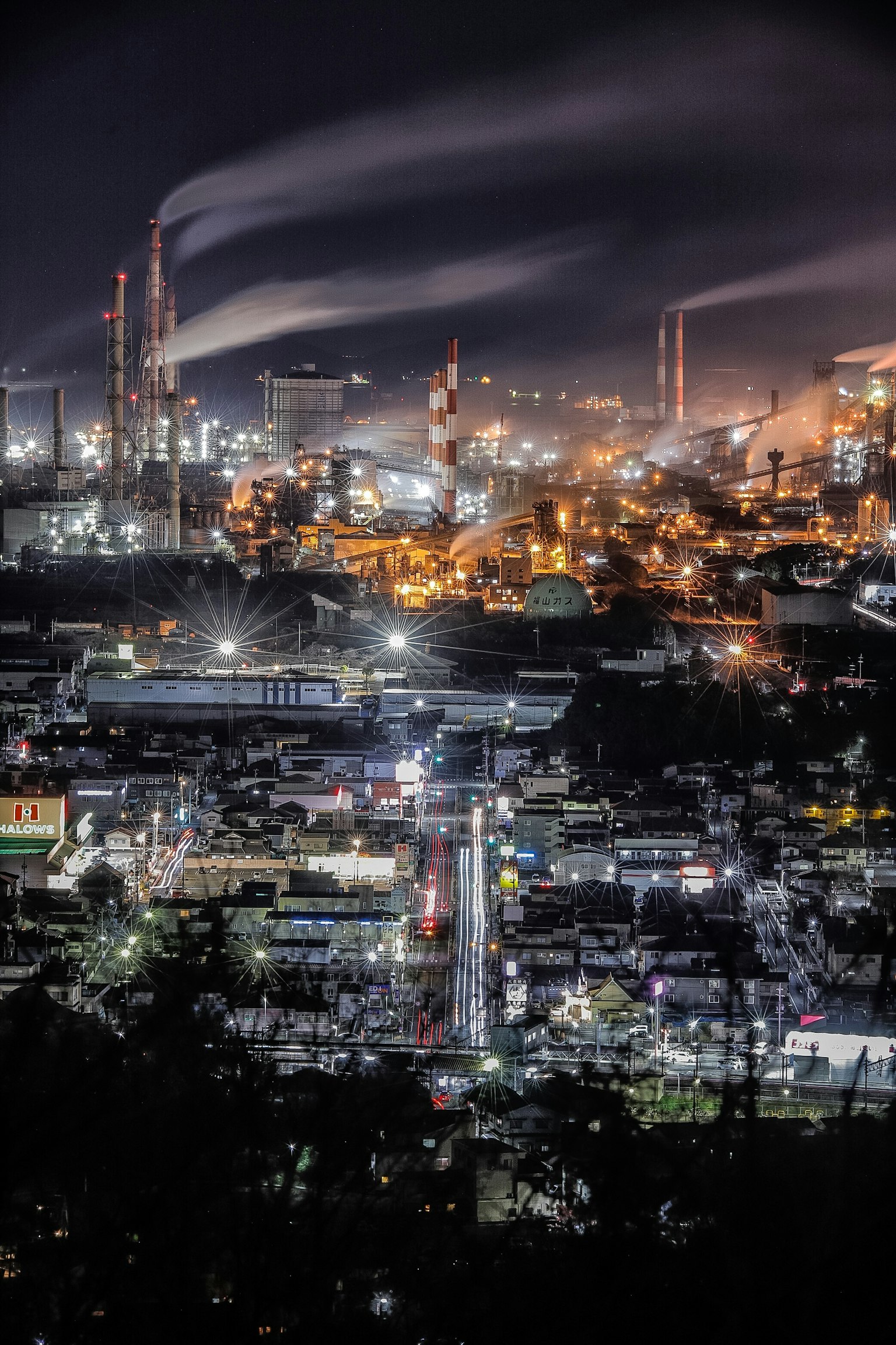 Vista nocturna de un área industrial con humo de chimeneas luces brillantes de fábricas y paisaje urbano