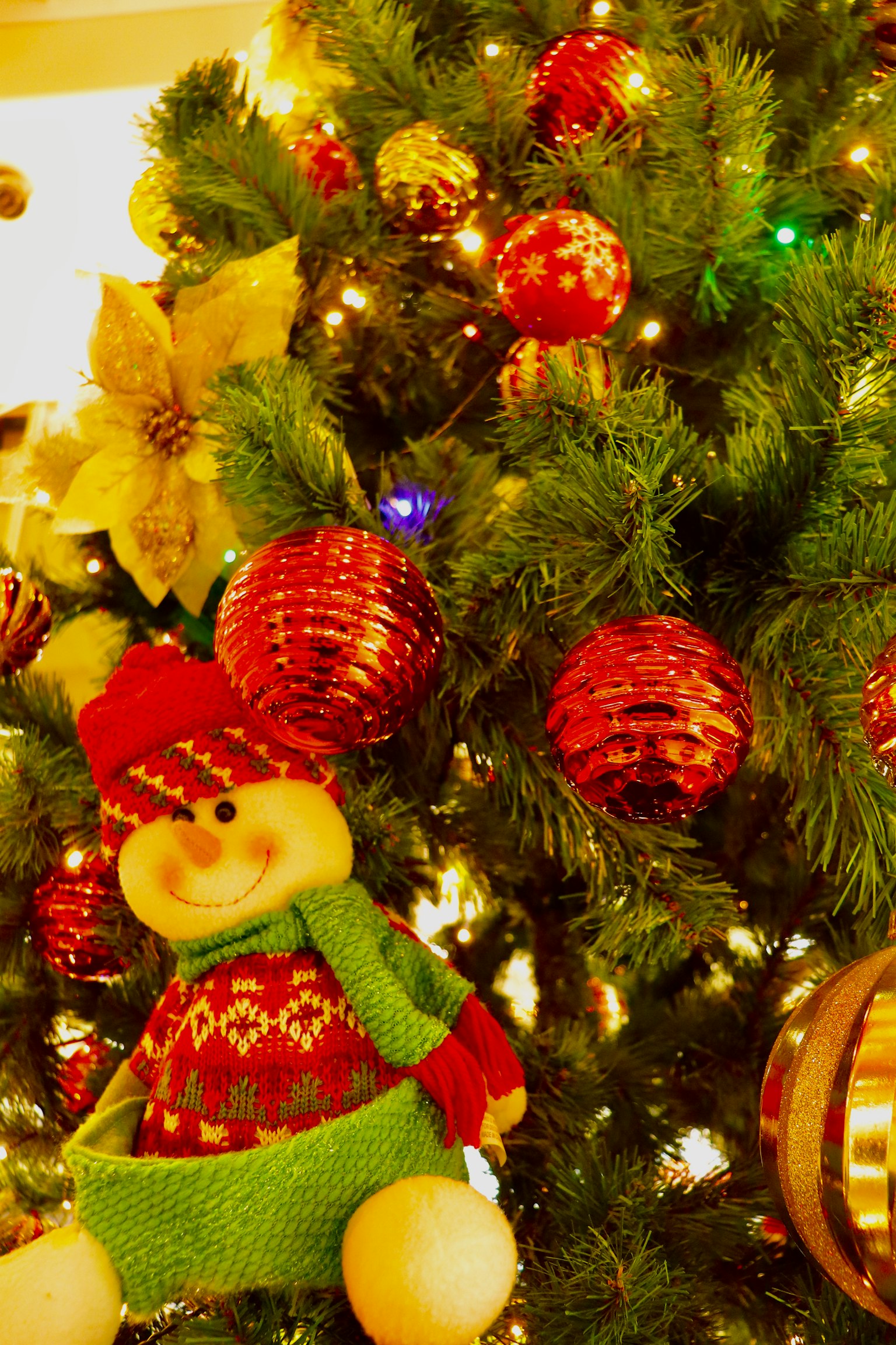 Pohon Natal dihias dengan ornamen merah dan hijau serta dekorasi boneka salju