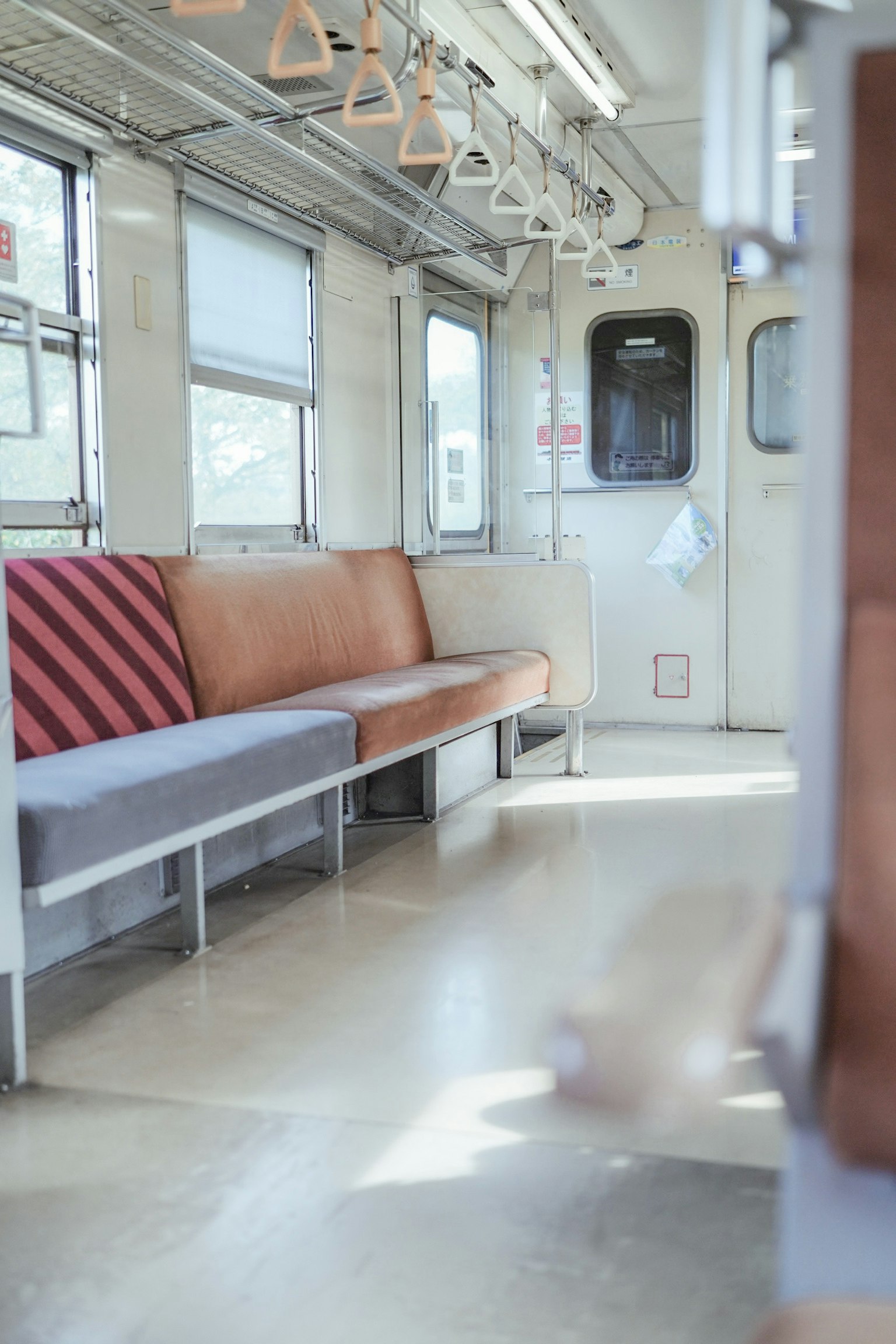 Interior de un vagón de tren casi vacío con bancos y pasamanos