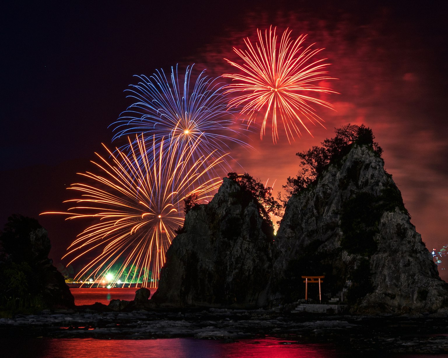 Hermoso paisaje con fuegos artificiales en el cielo nocturno y siluetas de rocas