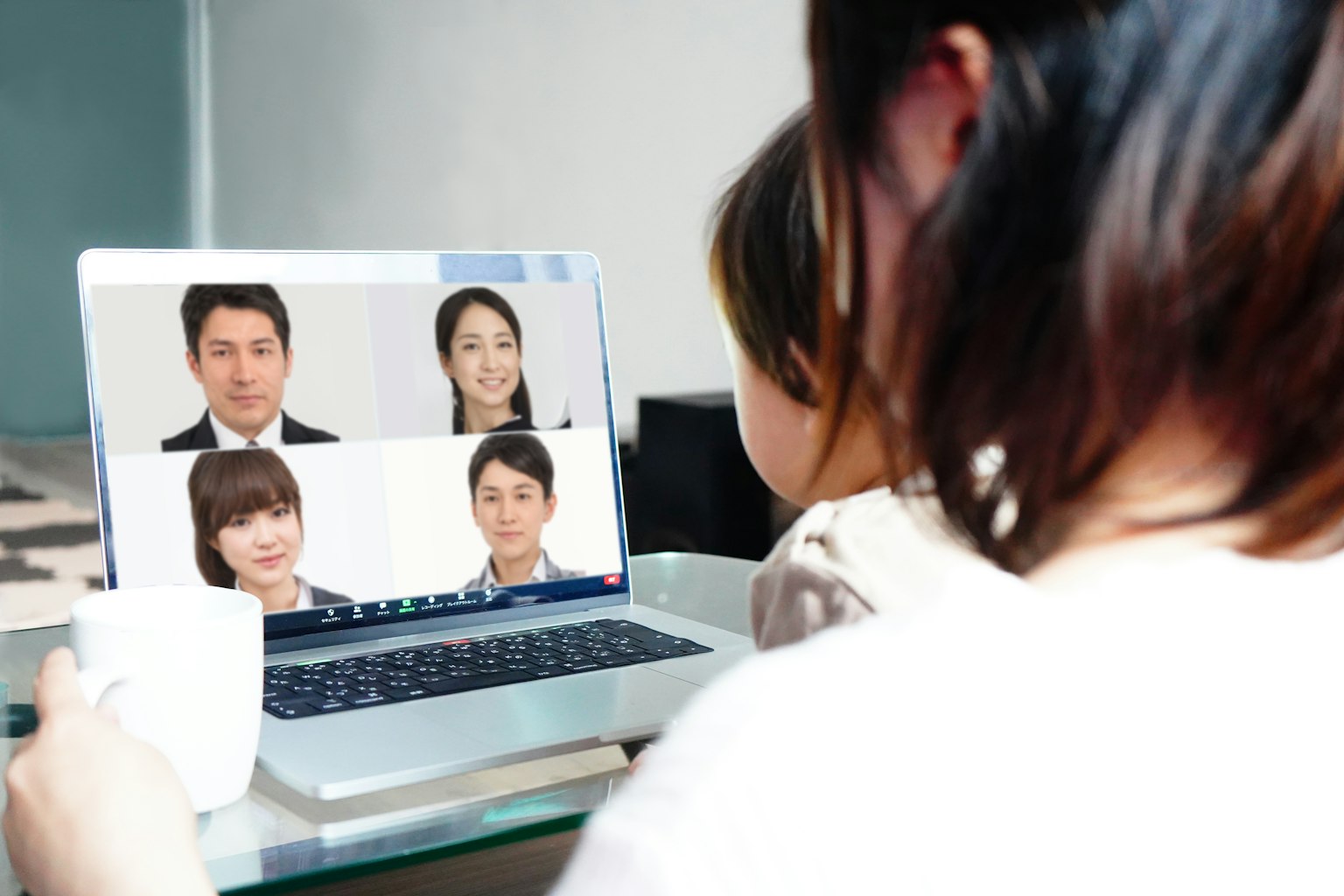 一名女性正在笔记本电脑上参加视频会议，屏幕上显示五名参与者