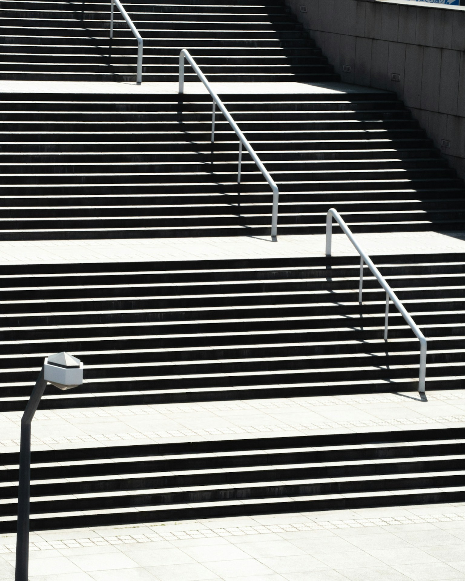 การออกแบบบันไดที่เรียบง่ายพร้อมราวจับและเงาที่โดดเด่น