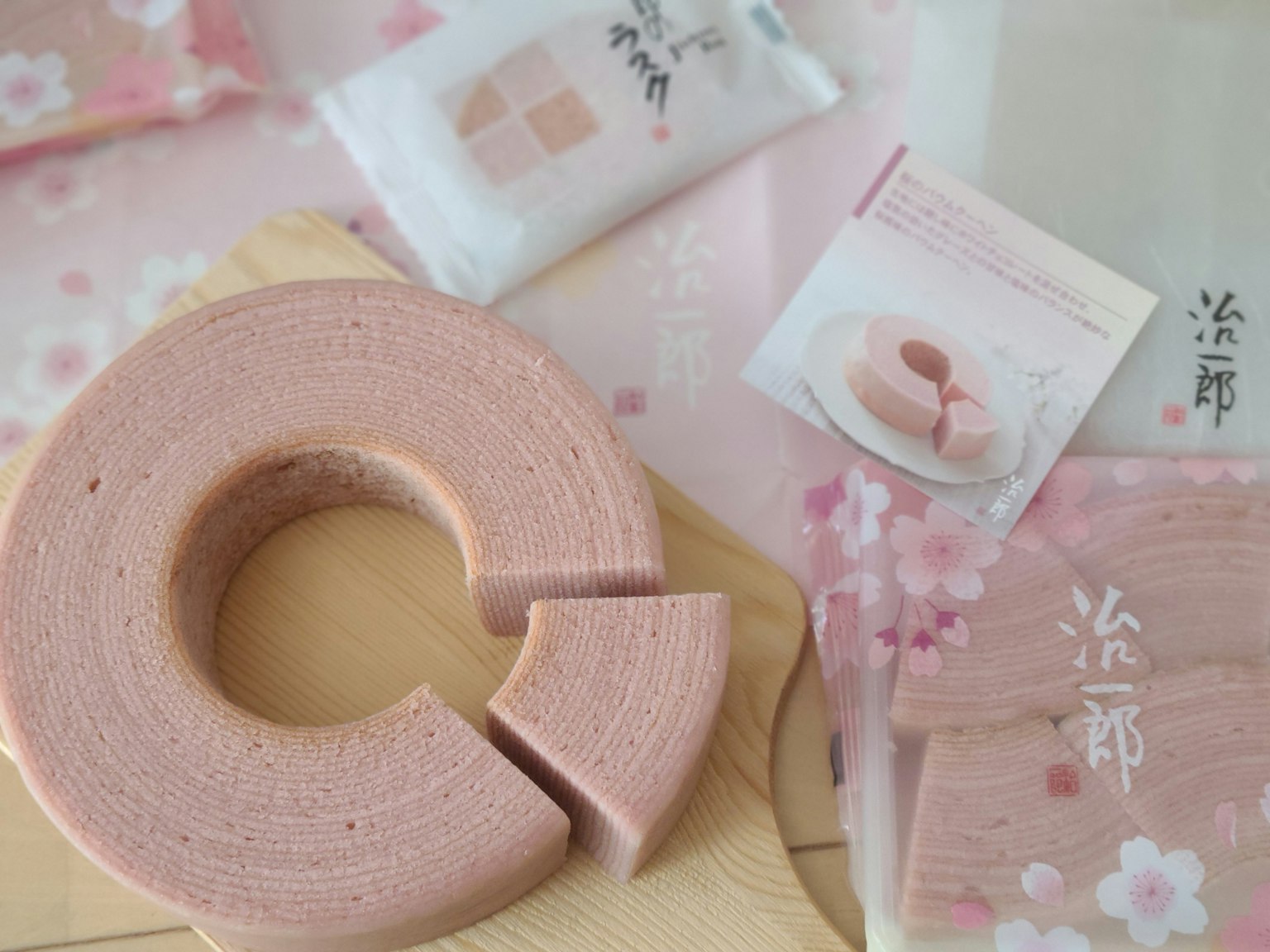 Baumkuchen rosa con tema de flores de cerezo colocado en un plato de madera