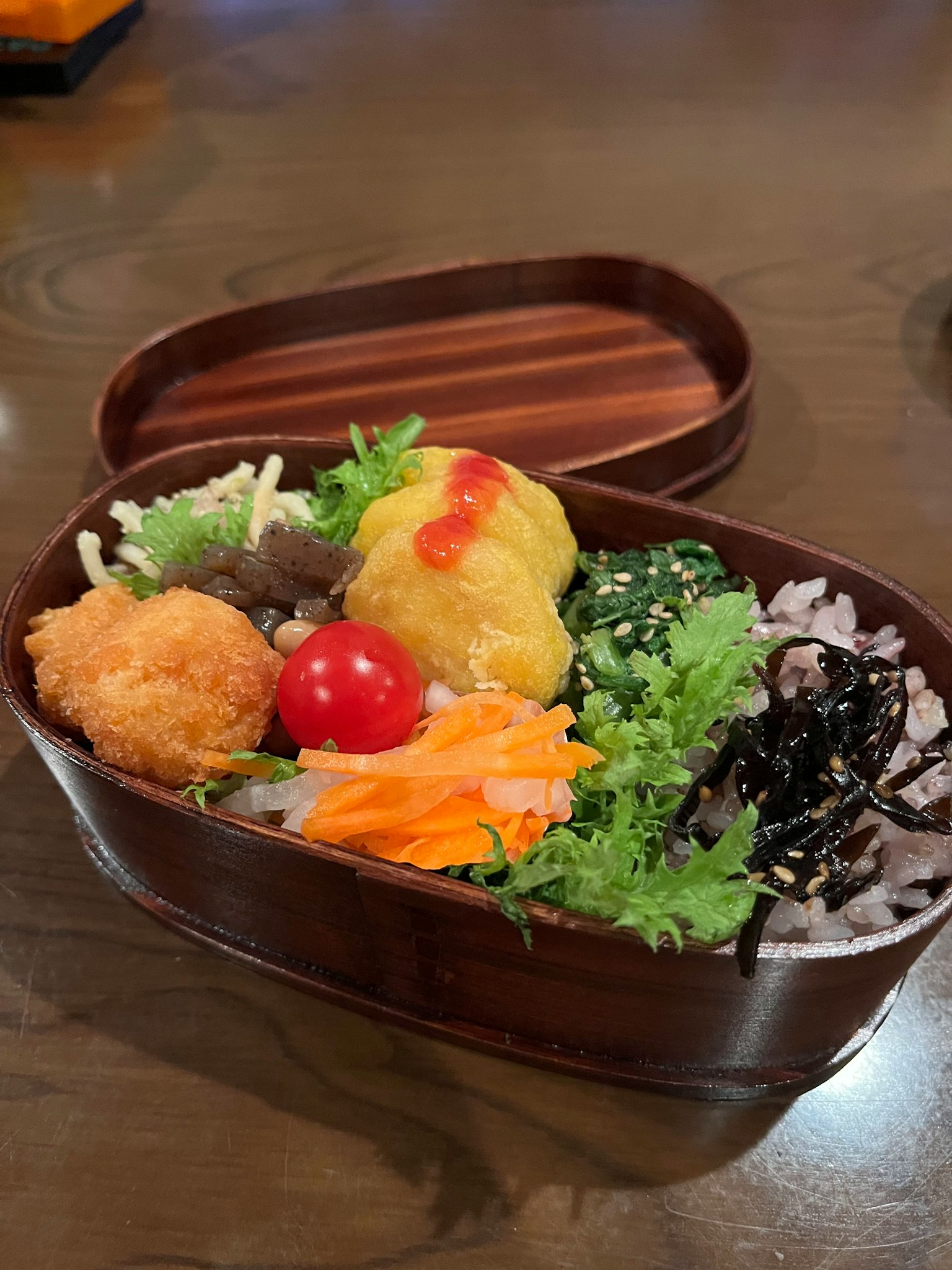 木製便當盒裝滿多樣菜餚包括新鮮蔬菜和米飯