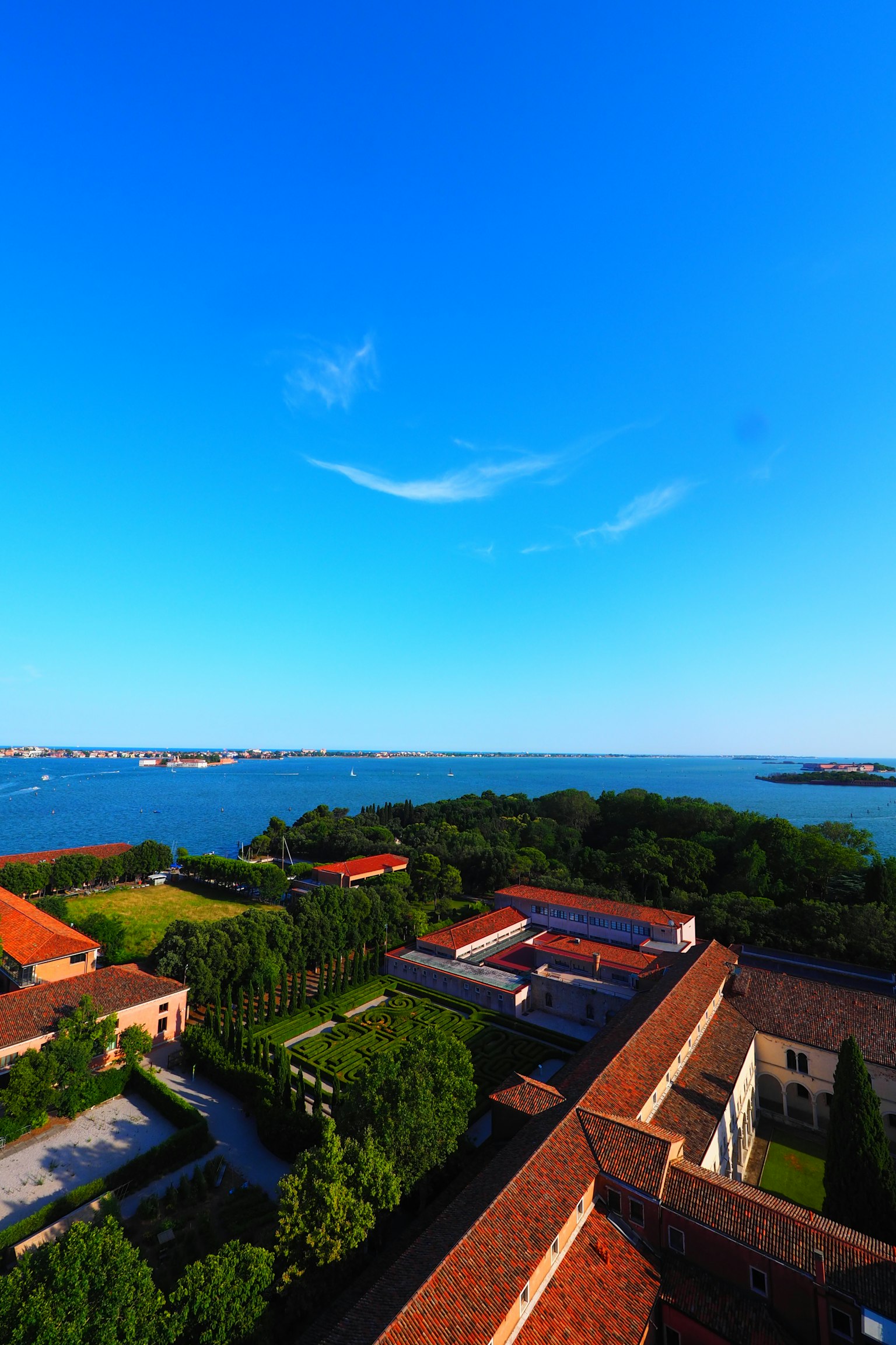 Una vista escénica con cielo azul y mar, paisaje verde y edificios de techos rojos